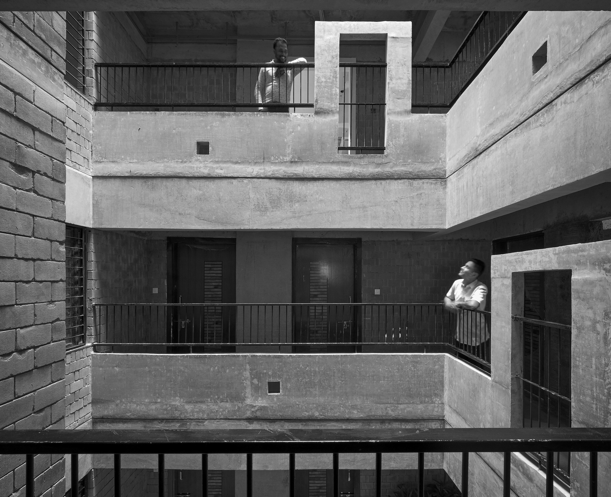 Black and white view of the interior courtyard with stacked balconies and a figure standing on one level