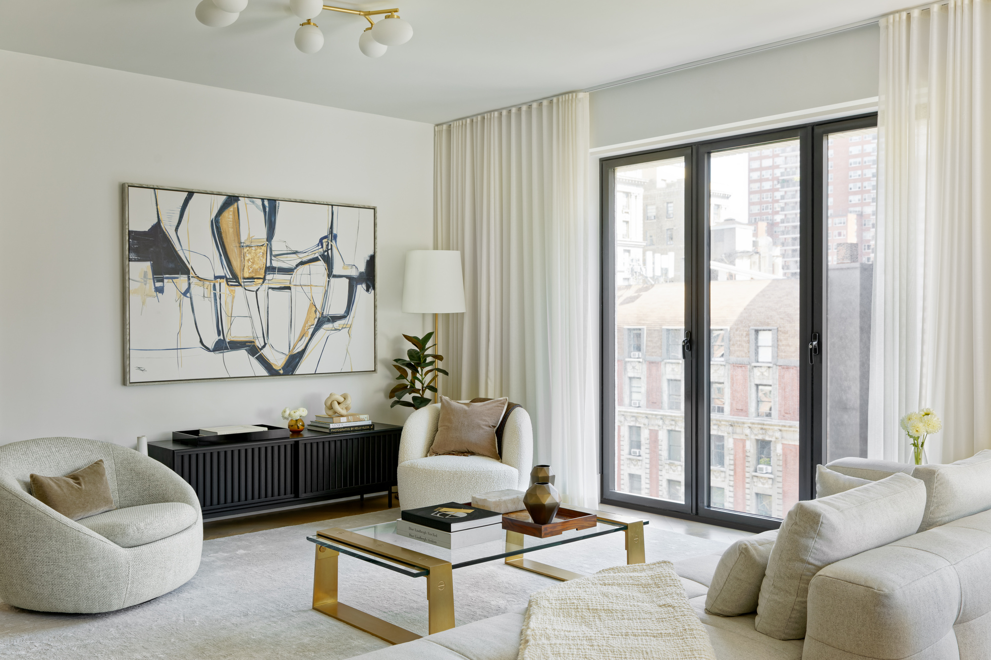 Living room with curved sofas and black-framed windows overlooking neighboring buildings