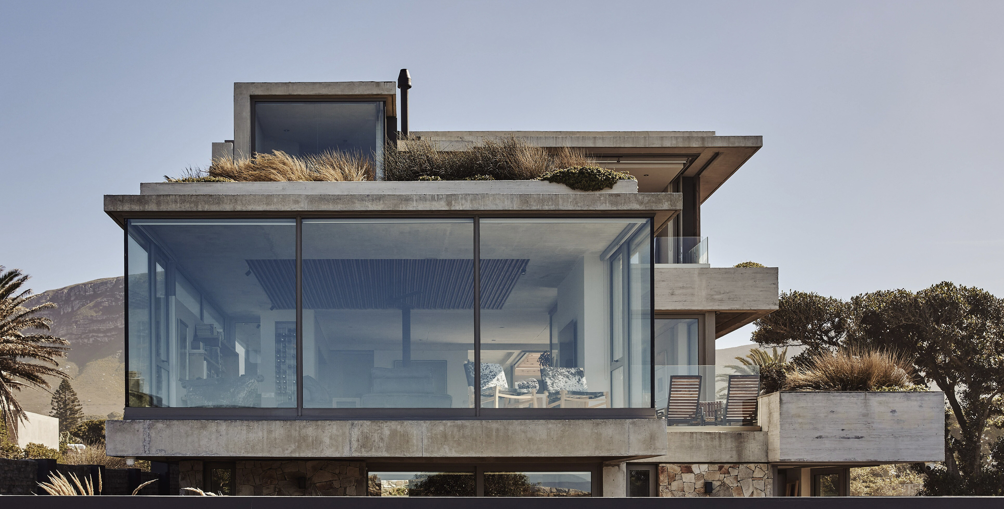 Rear elevation with floor-to-ceiling glazing, planted roof terraces and distant mountains