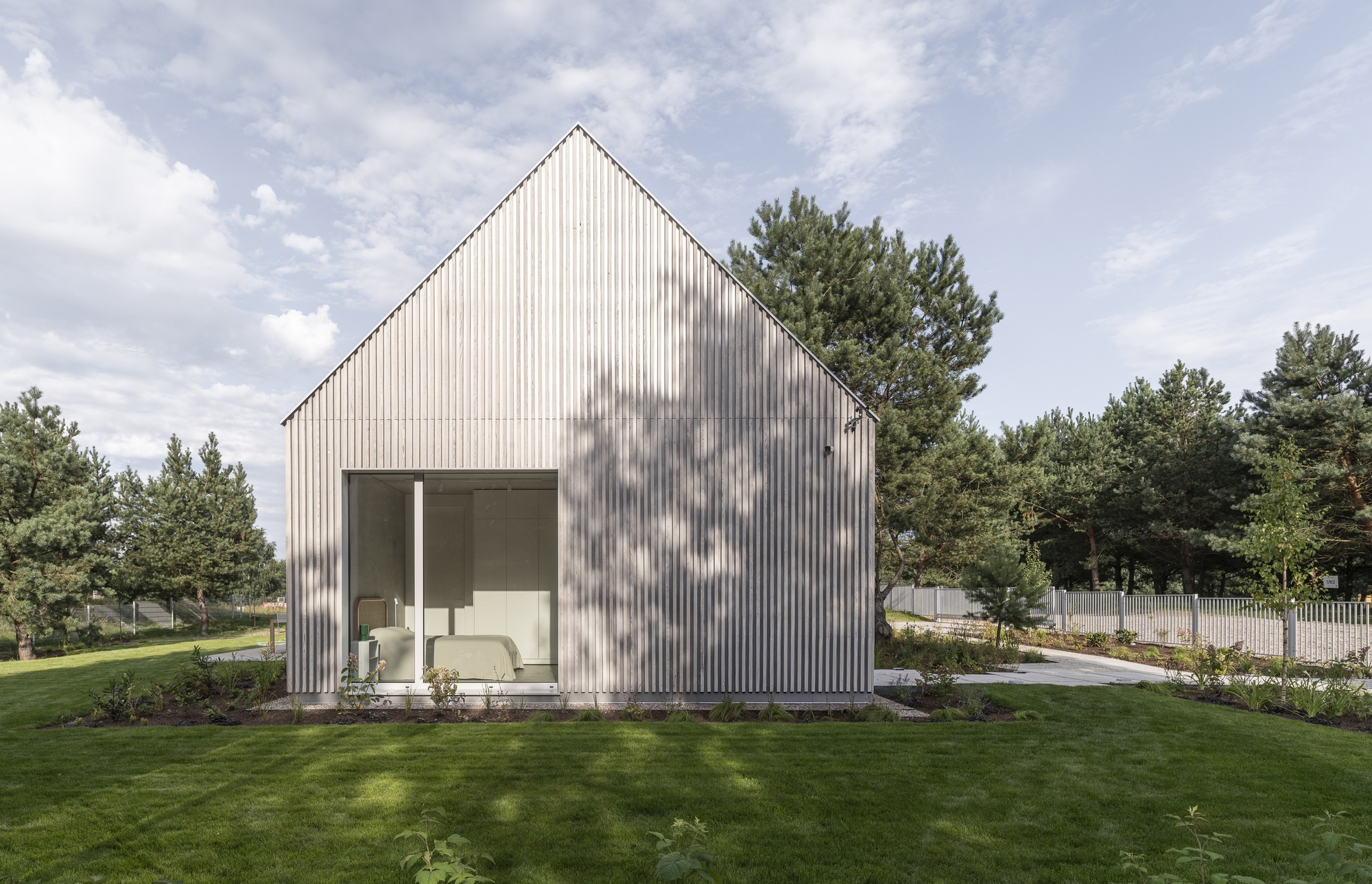 Garden elevation showing the corrugated metal cladding and recessed terrace with tree shadows on the facade
