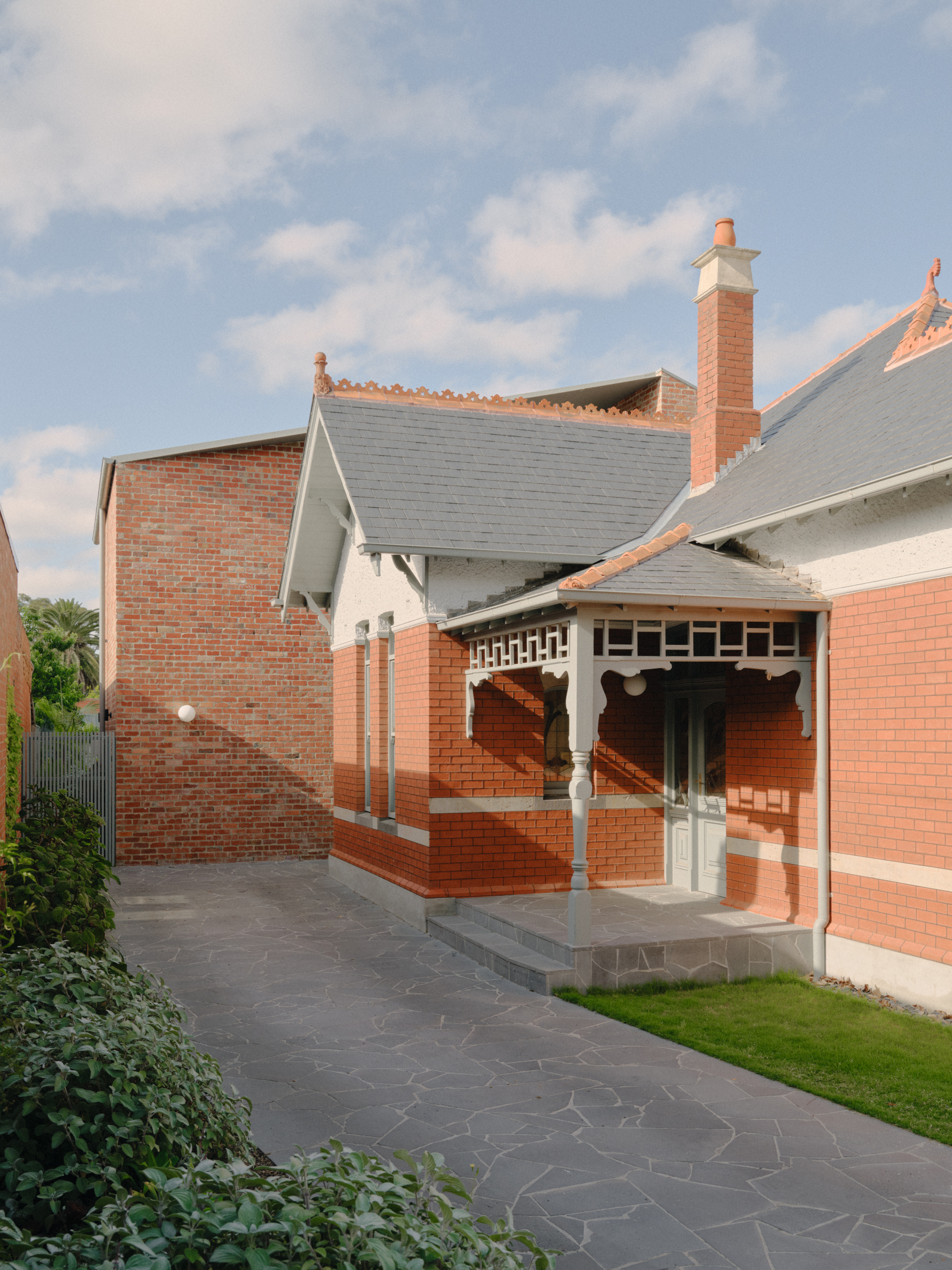 Rear courtyard showing red brick porch with decorative timber brackets and dark stone paving