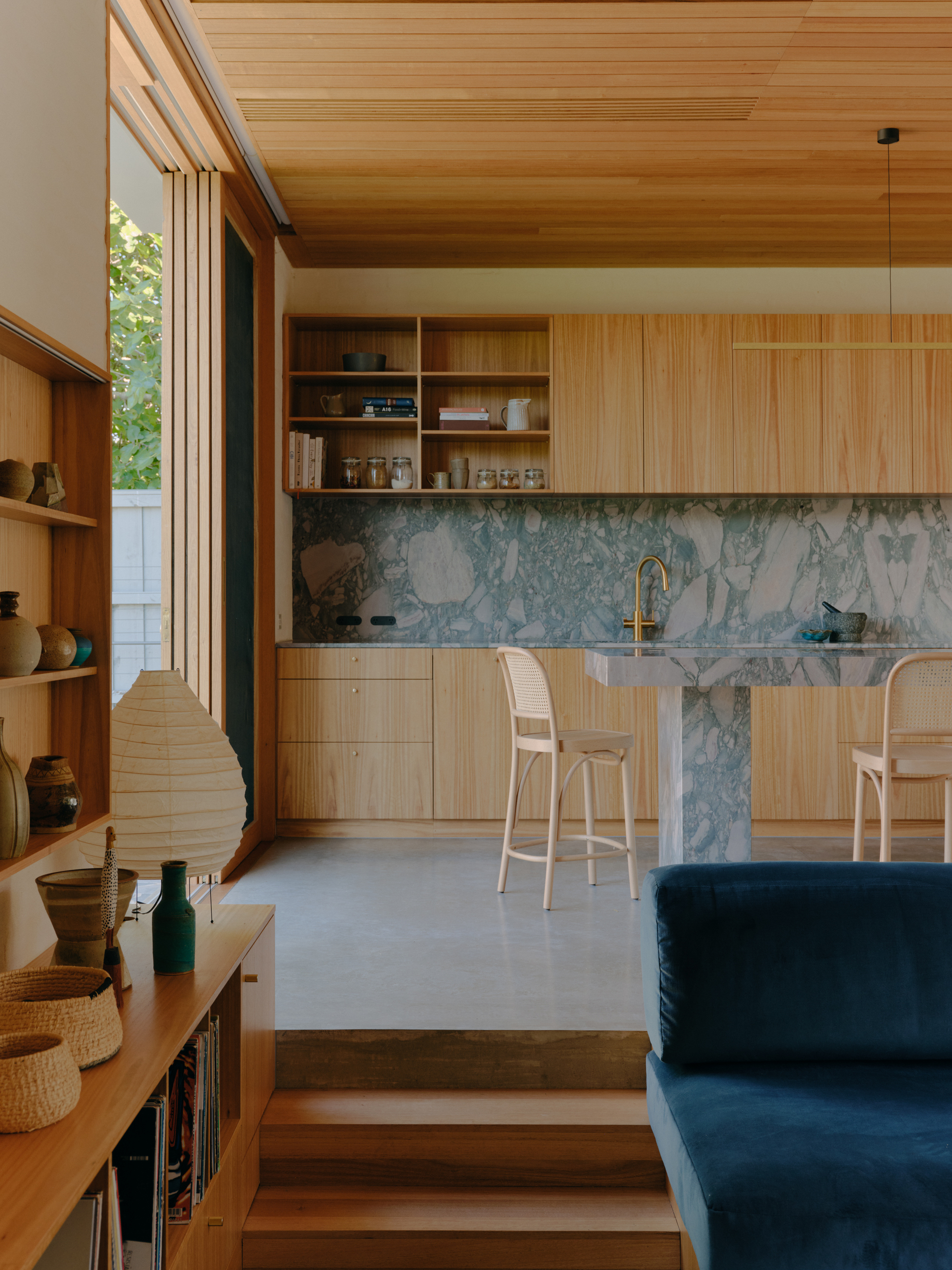 Kitchen with vertical timber cabinetry, blue marble island and natural light through clerestory windows