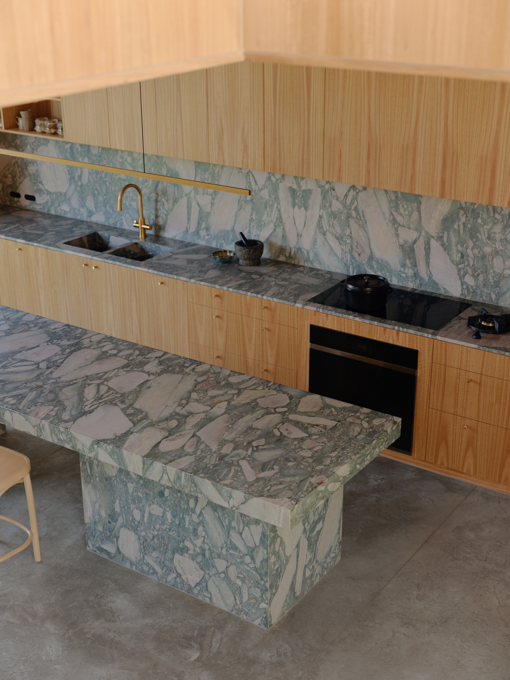 Kitchen with pale green veined marble island and backsplash paired with timber veneer cabinetry