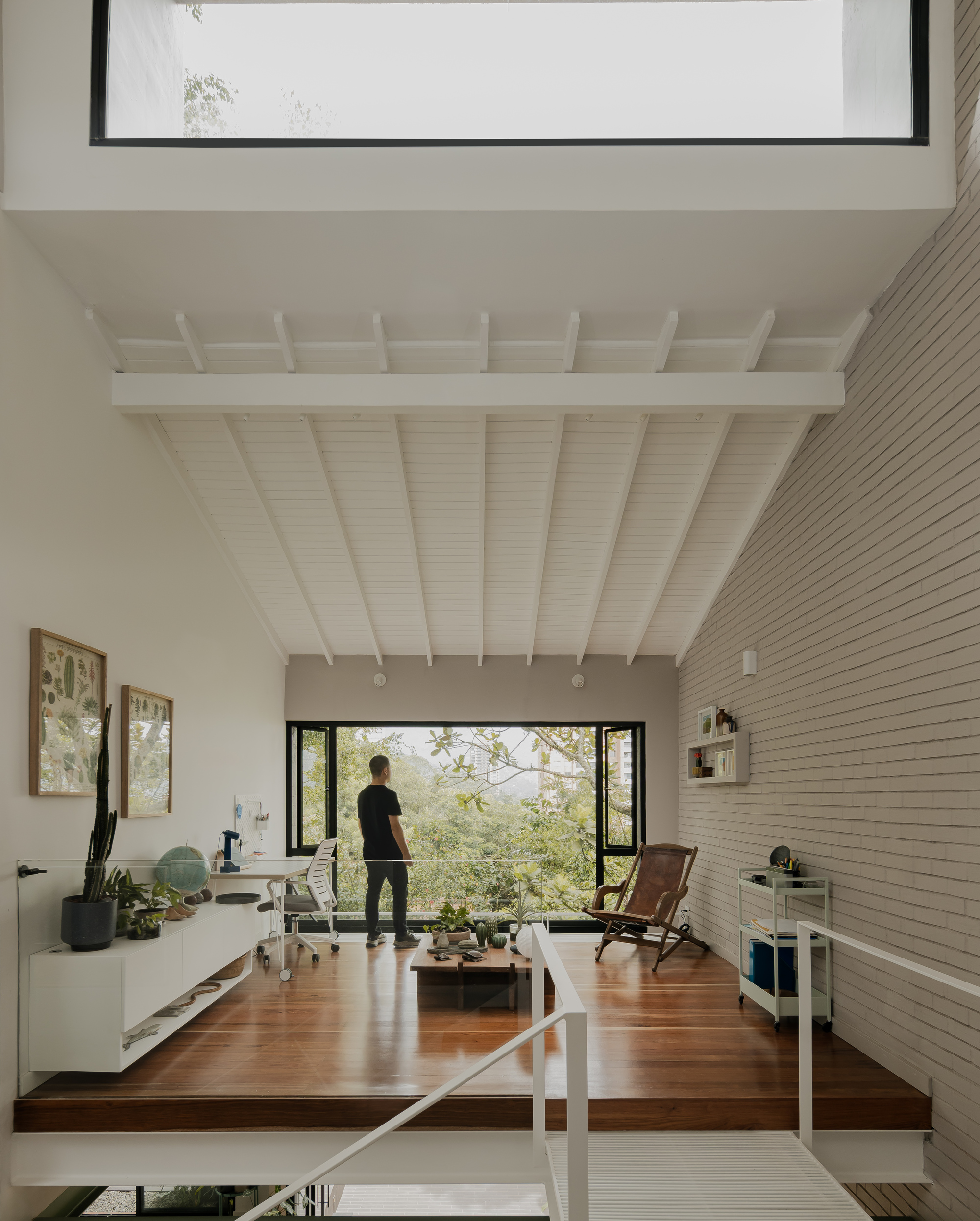 Split-level study with horizontal timber cladding and figure standing at glazed doors framing garden view