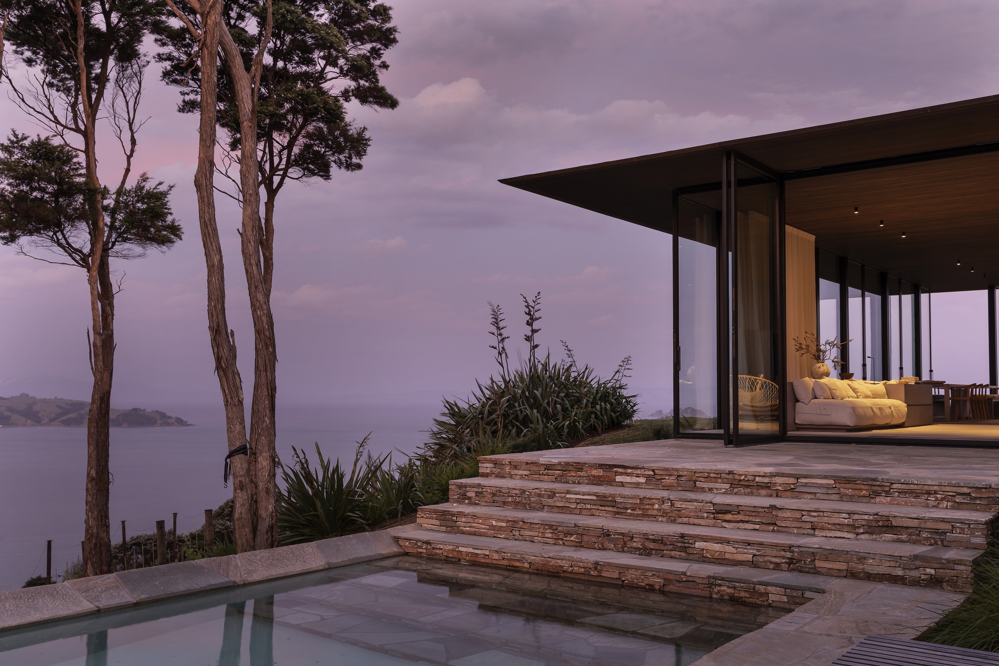 Terrace with layered stone steps and infinity pool overlooking the ocean at dusk