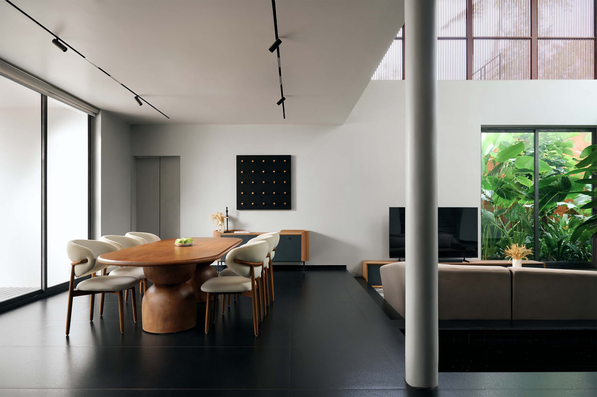 Open dining and living space with circular timber table and views to planted courtyard through glazing