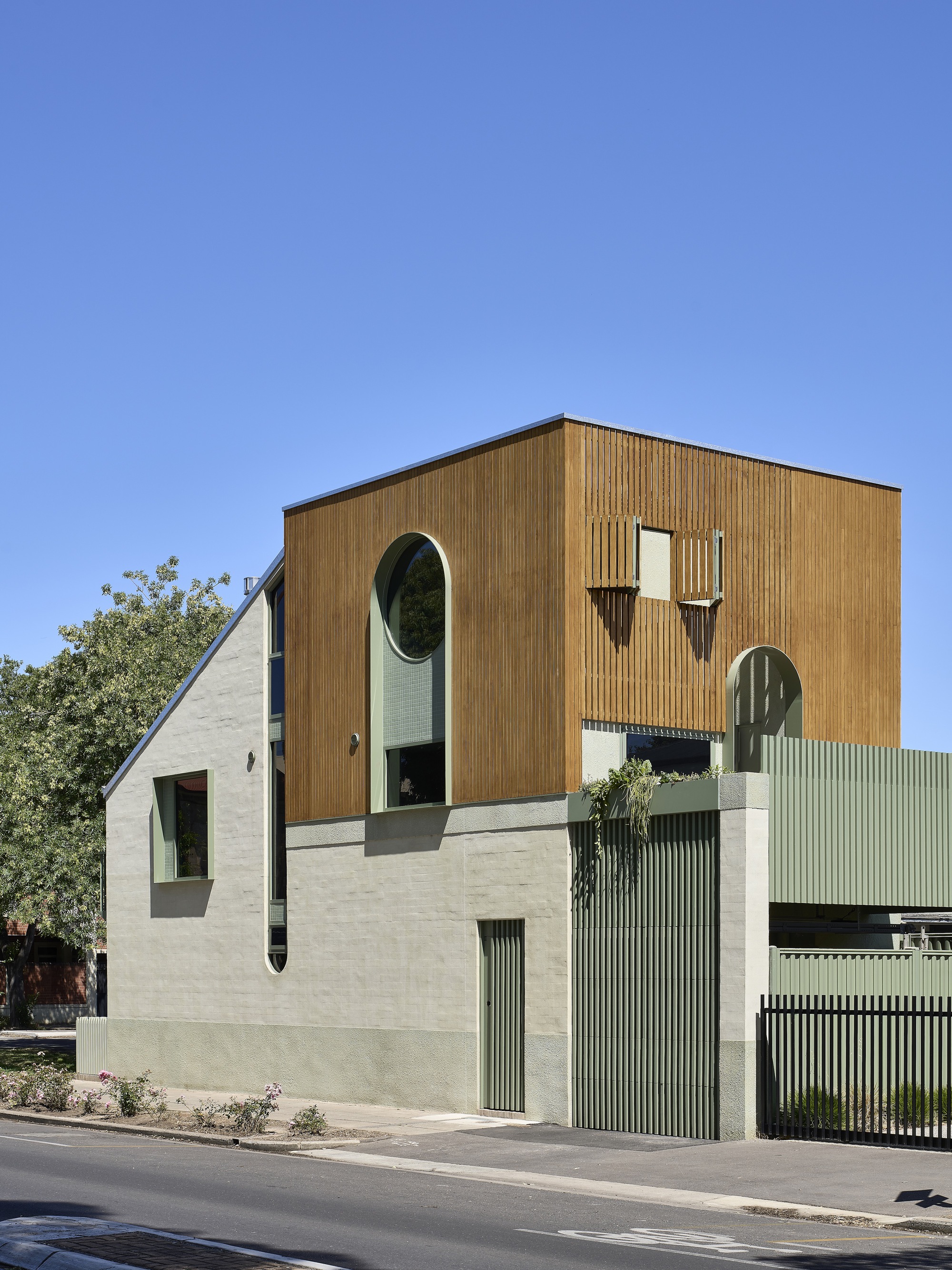 Street elevation with mixed material facade of timber cladding, pale render, and corrugated metal screening