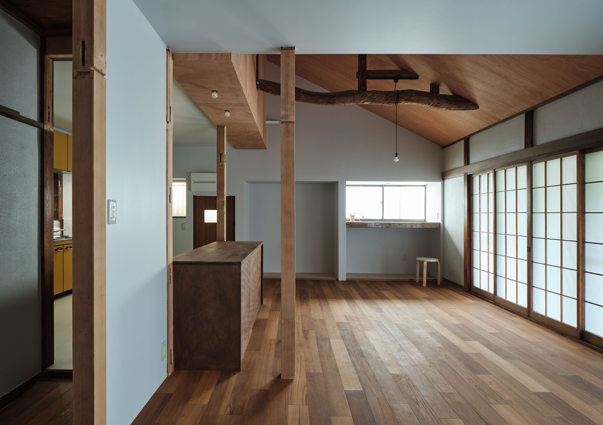 Open interior with exposed timber columns and a sculptural wood ceiling plane above timber flooring