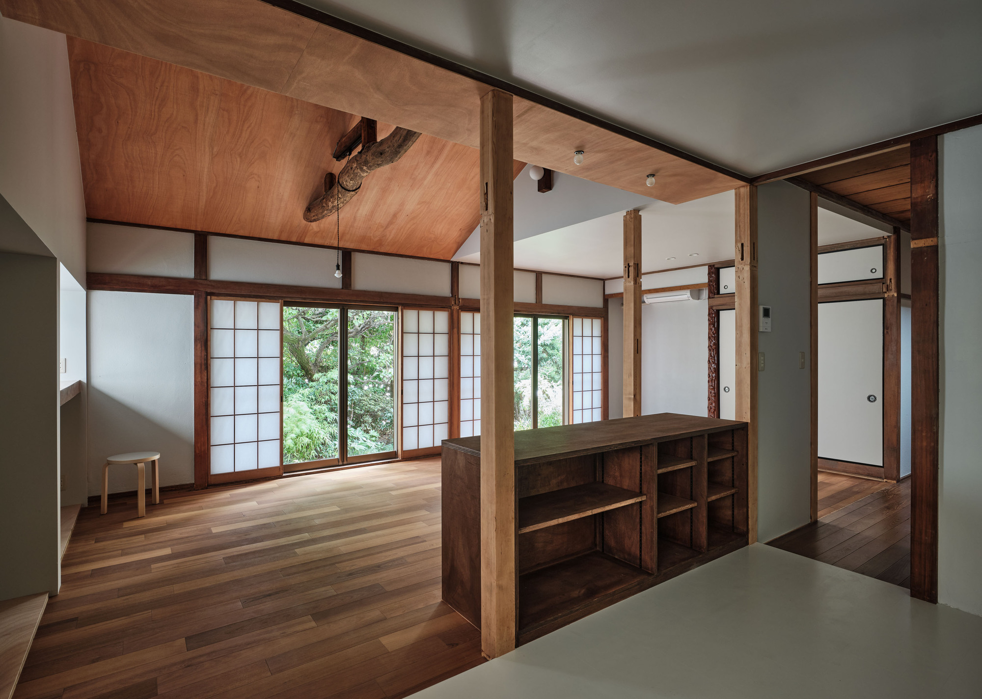 Interior room with translucent sliding screens opening to greenery and a low timber storage unit