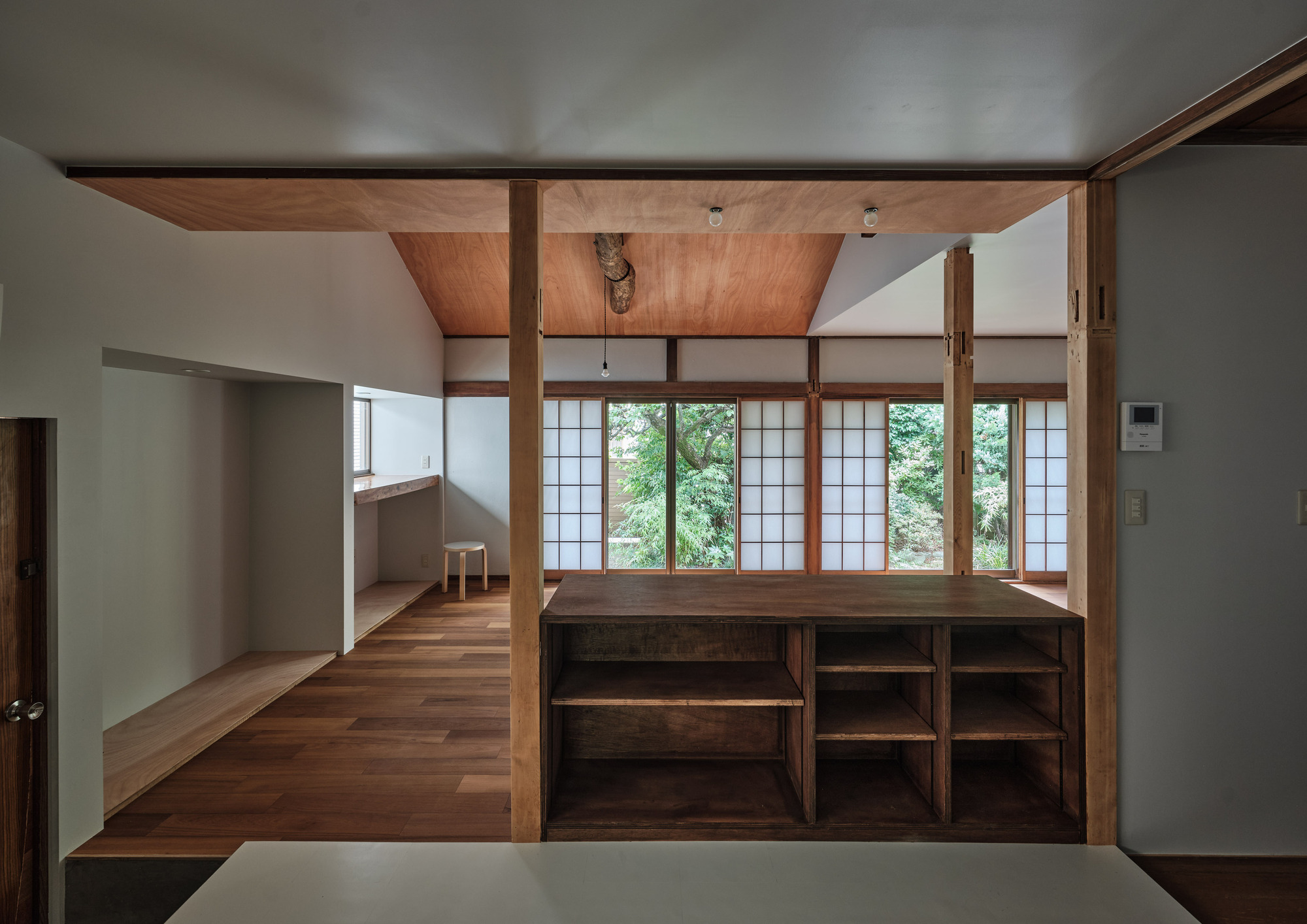 Raised platform with built-in shelving facing shoji screens overlooking green foliage outside