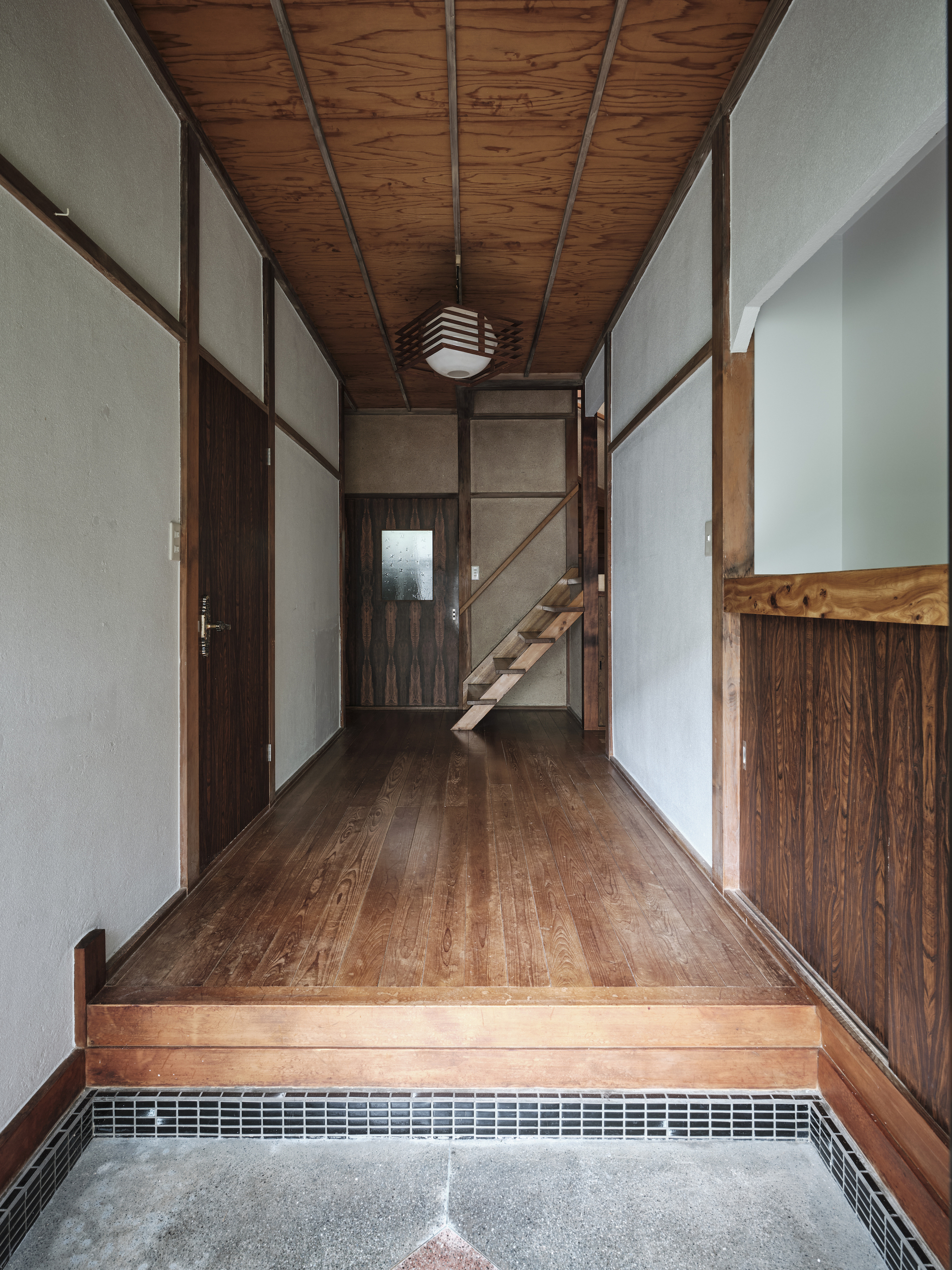 Entry hall with timber ceiling, paper walls, and a raised floor platform leading to an open staircase