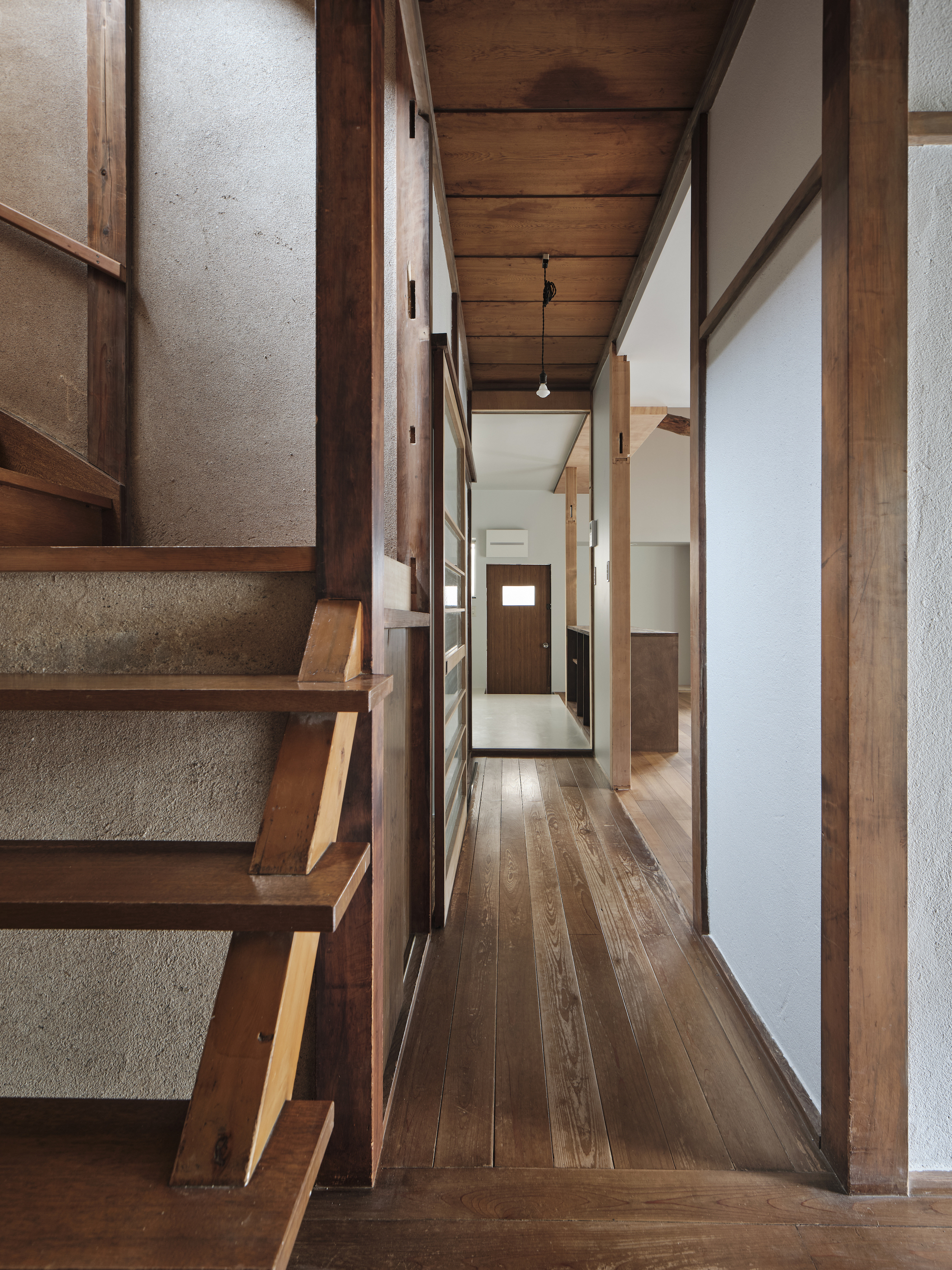 Timber staircase with open risers adjacent to a narrow hallway with paper screen walls