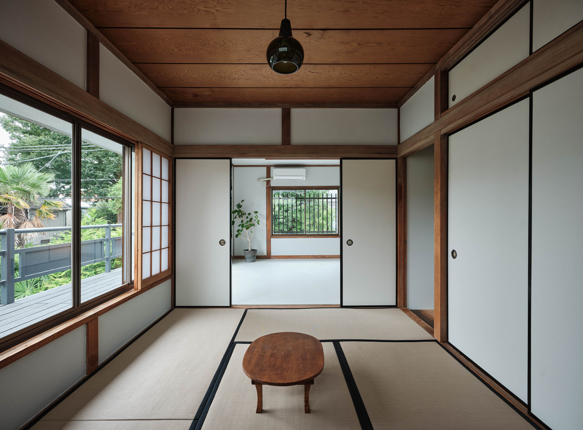 Tatami-floored room with sliding screens and timber ceiling framing a view through to an adjoining space