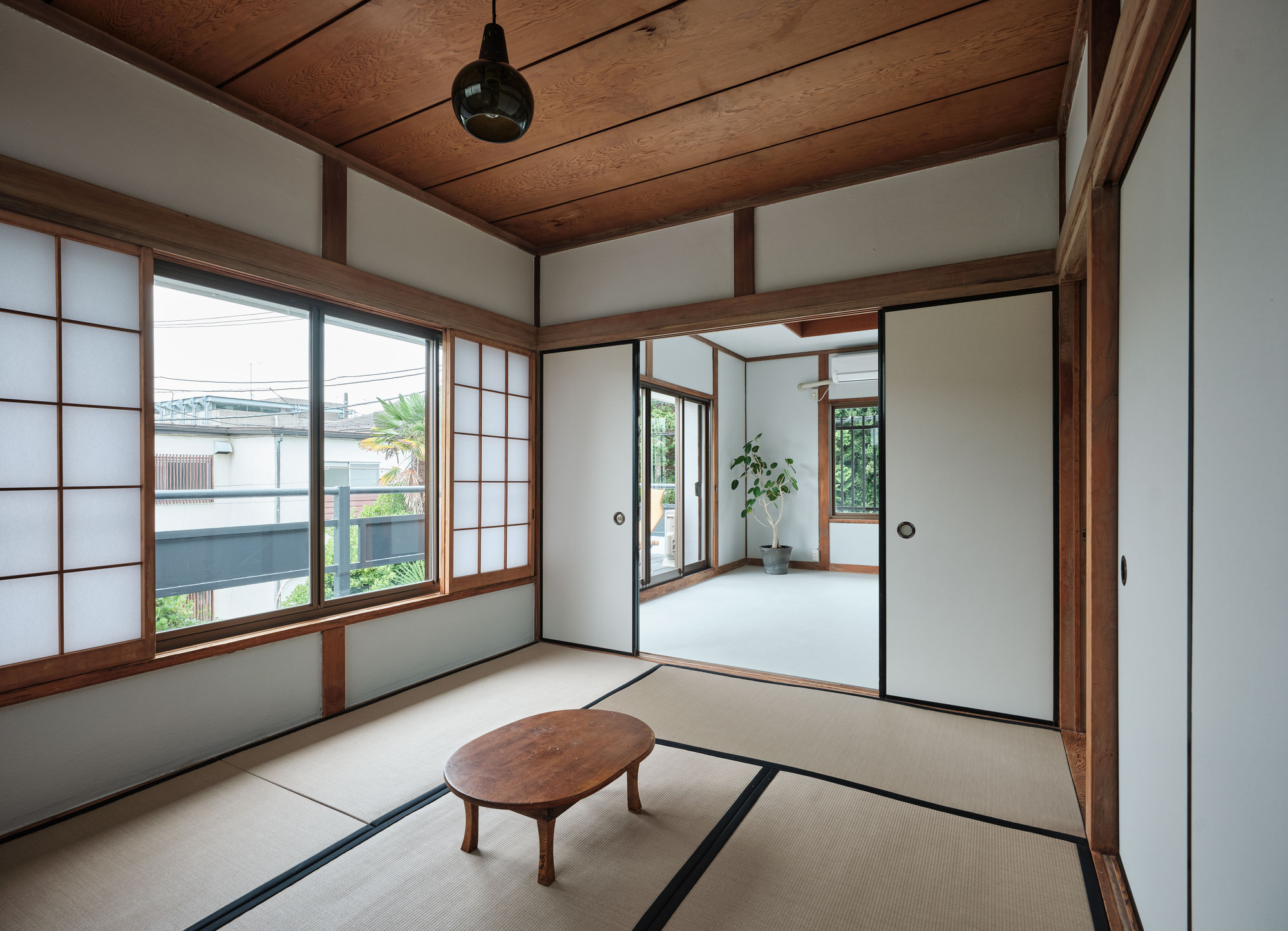 Connected tatami rooms with timber frame construction and sliding translucent screens filtering daylight from the garden