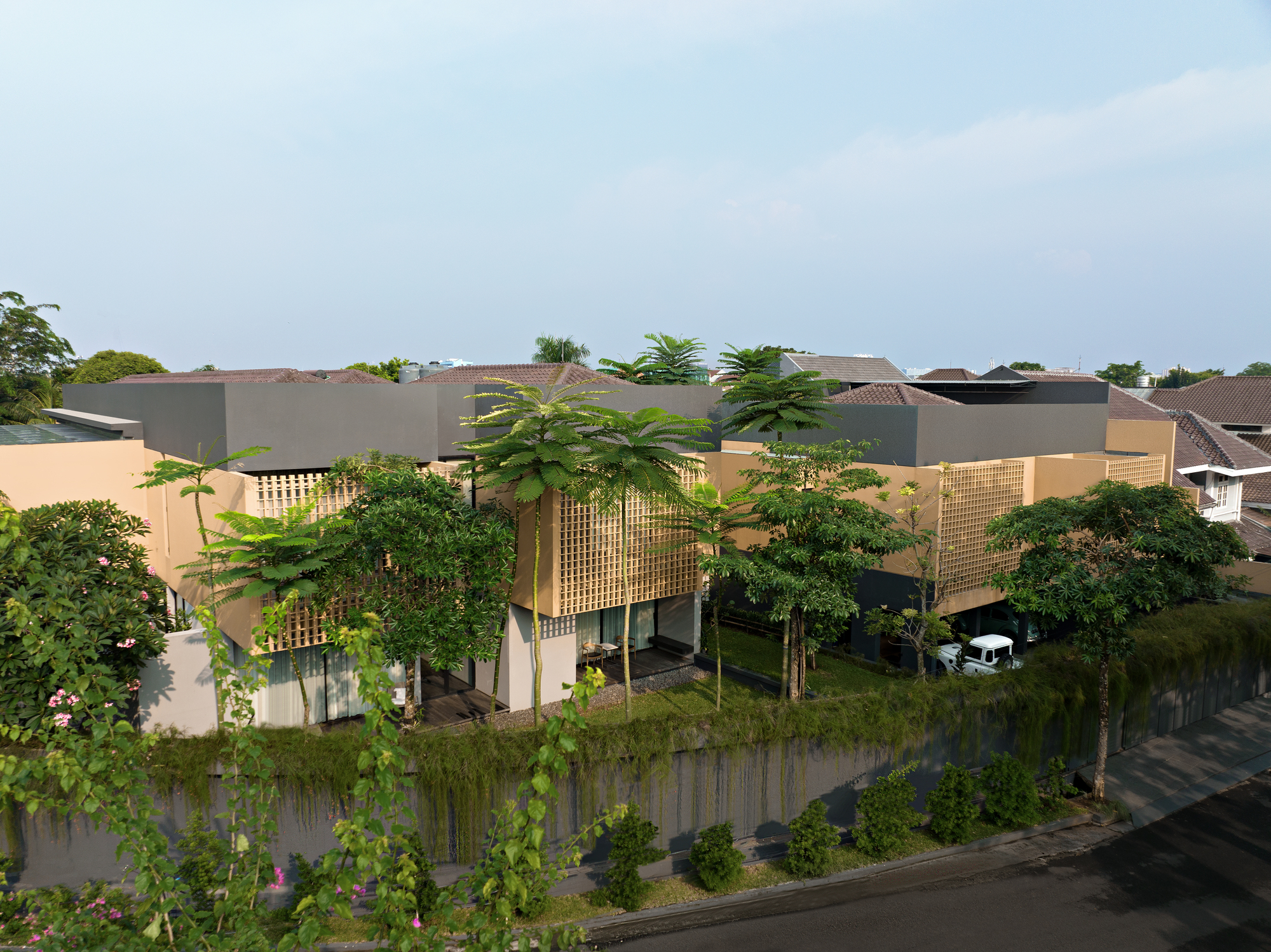 Elevated perspective of the compound showing flat roofs, lattice screens, and dense vegetation along the street