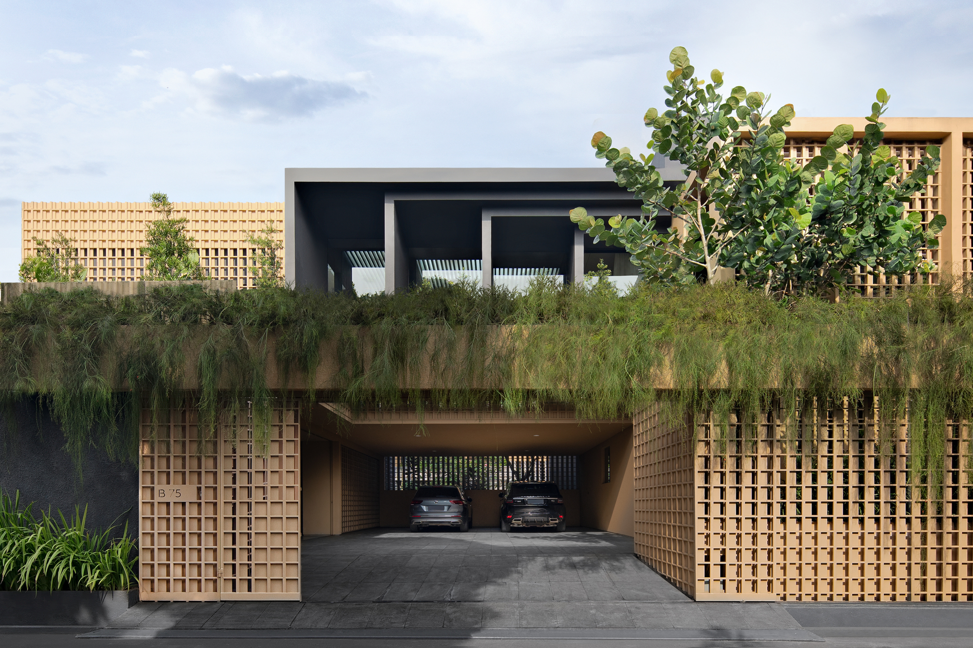 Street view of the entrance with sliding lattice gates opening to a carport beneath planted terraces