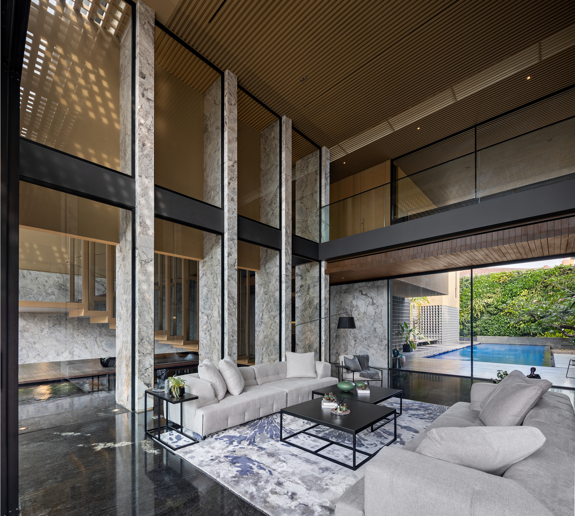 Double-height living room with concrete columns, steel mezzanine bridge and timber slat ceiling filtering daylight