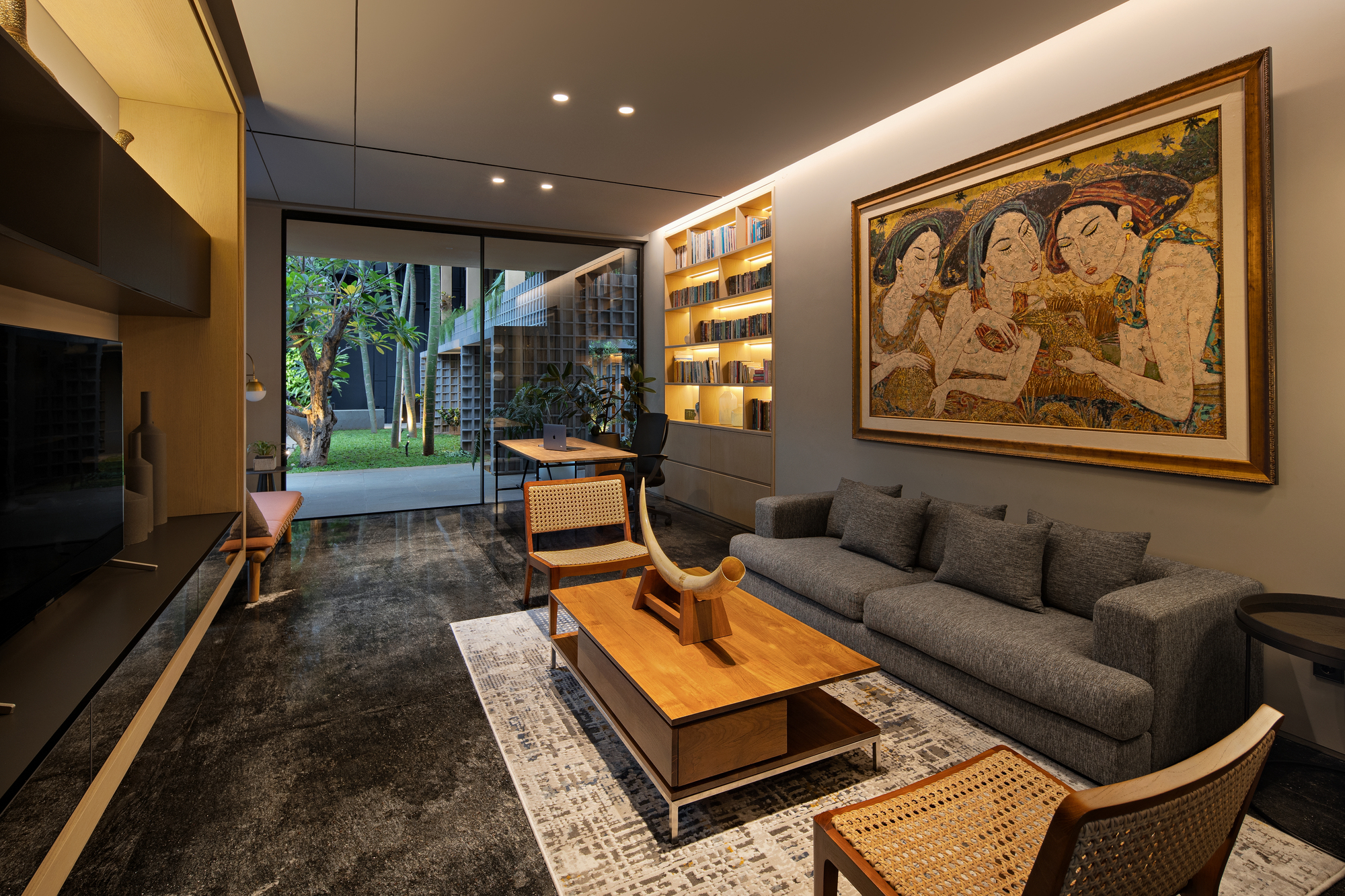 Living room opening to garden courtyard through floor-to-ceiling glass doors at dusk