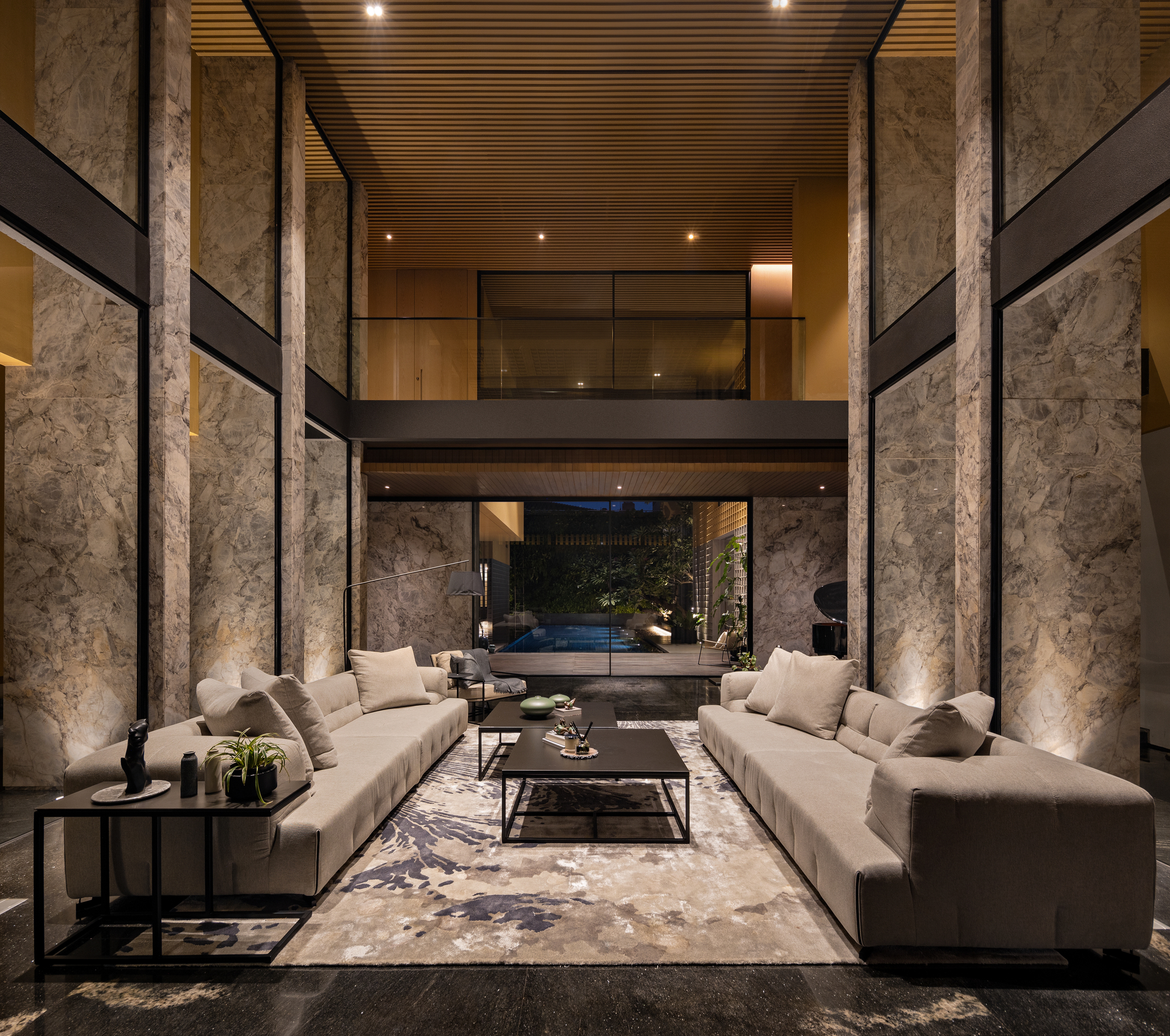 Double-height living space with rough stone columns and slatted timber ceiling under evening light