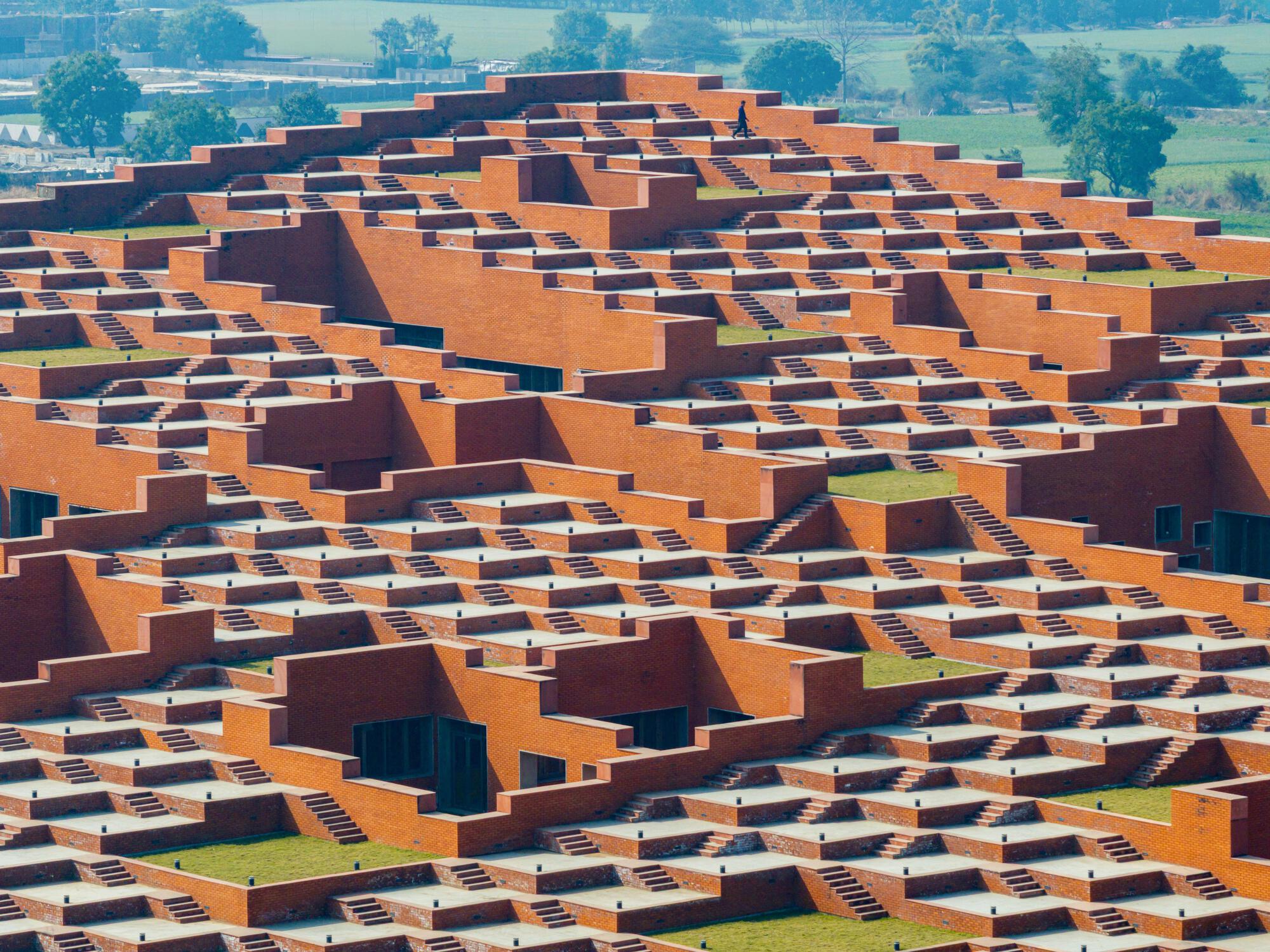Aerial view of terraced orange and brown brick roofscape with stepped volumes and planted courtyards