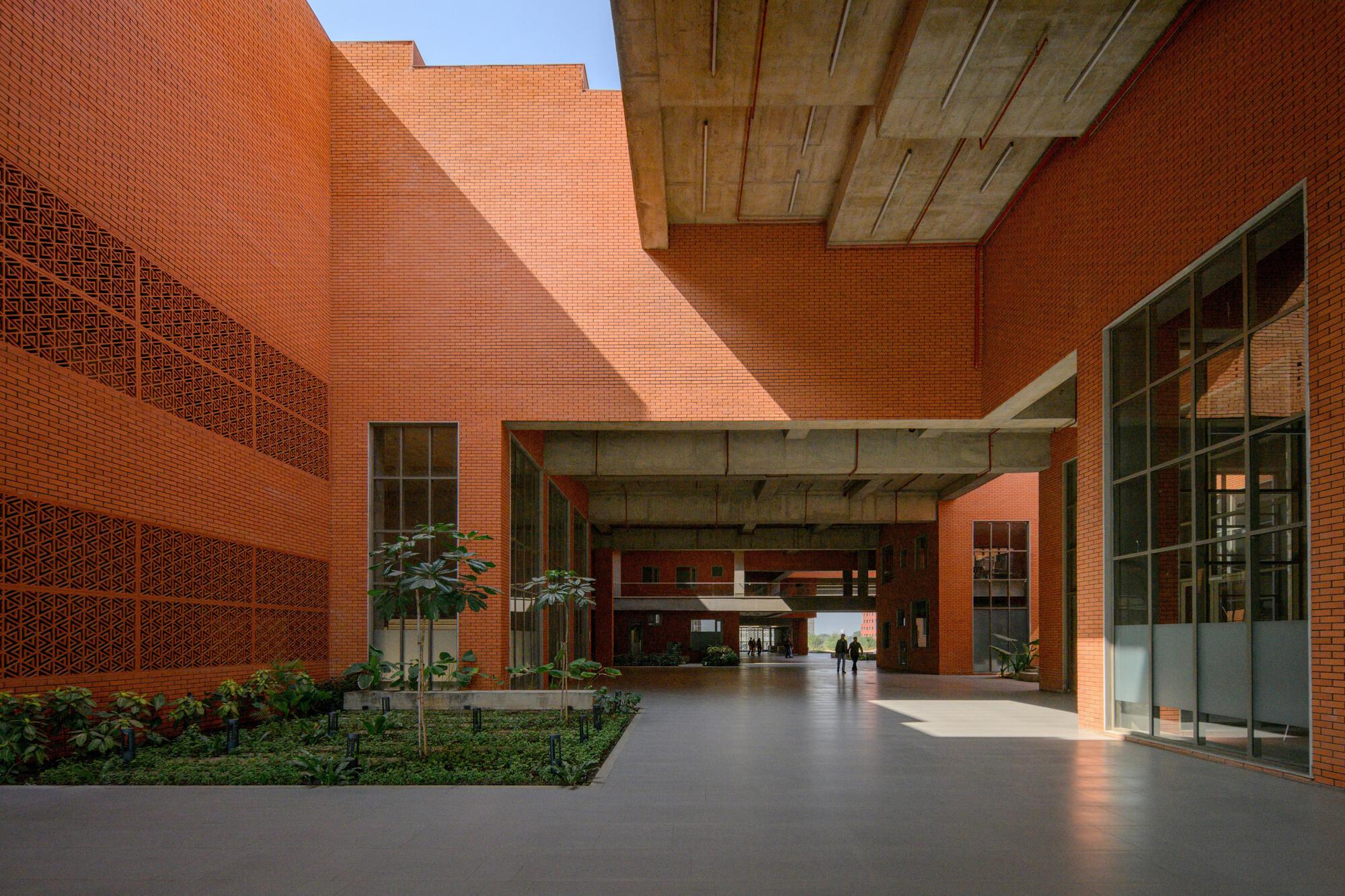 Ground-level view of a covered passageway with exposed concrete beams and planted landscape beds