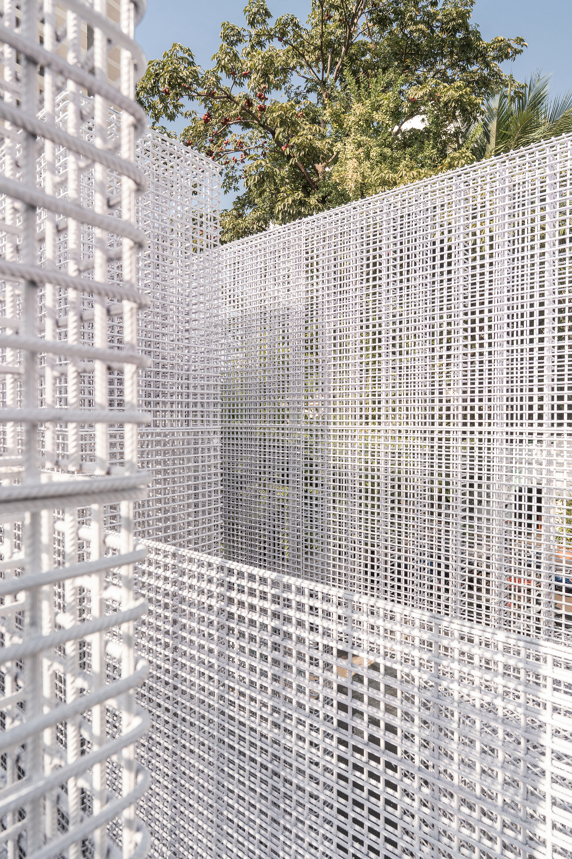 Close-up of white gridded mesh screen showing corner intersection with trees visible beyond