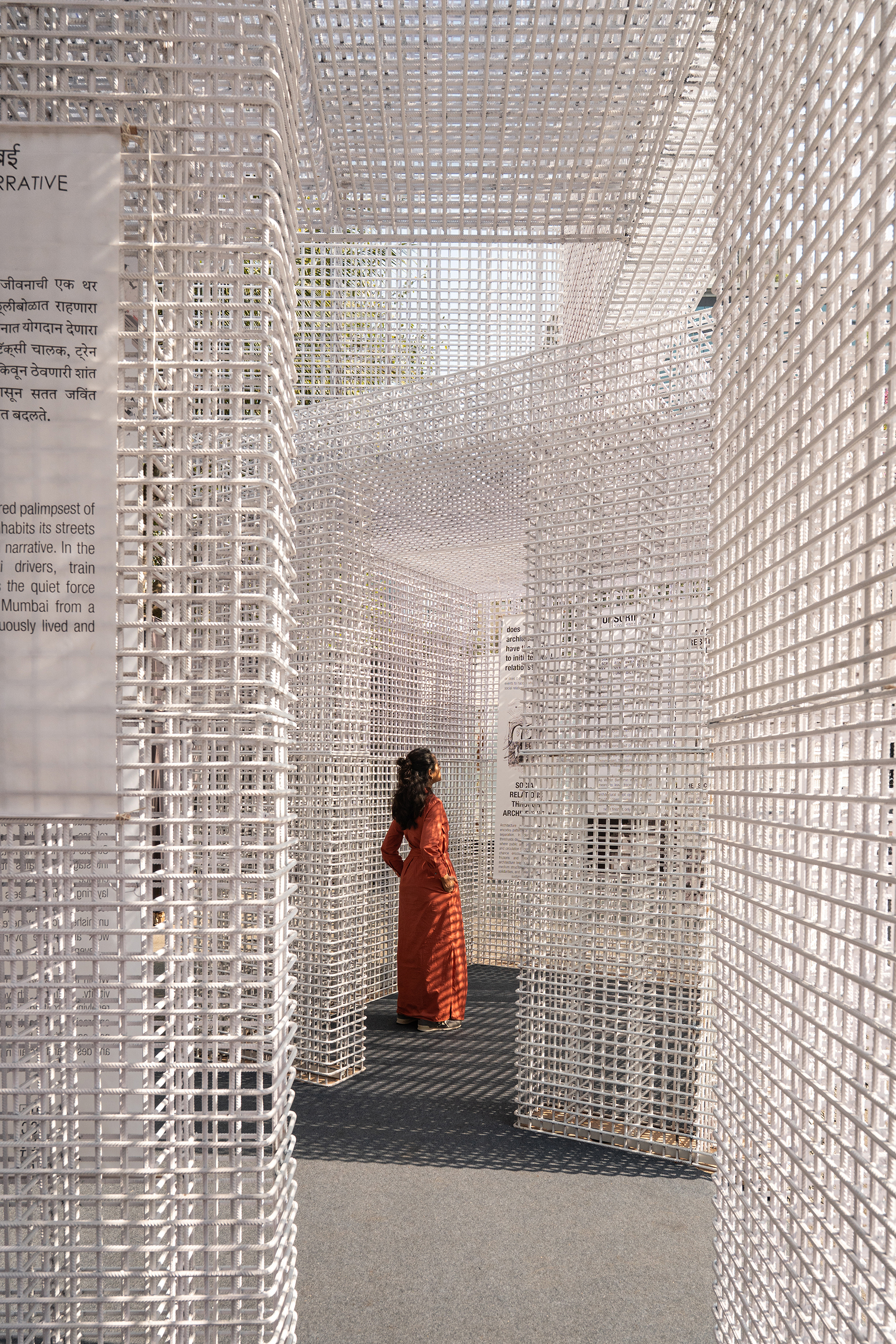 Interior chamber formed by white lattice walls with a visitor in orange standing beneath filtered daylight