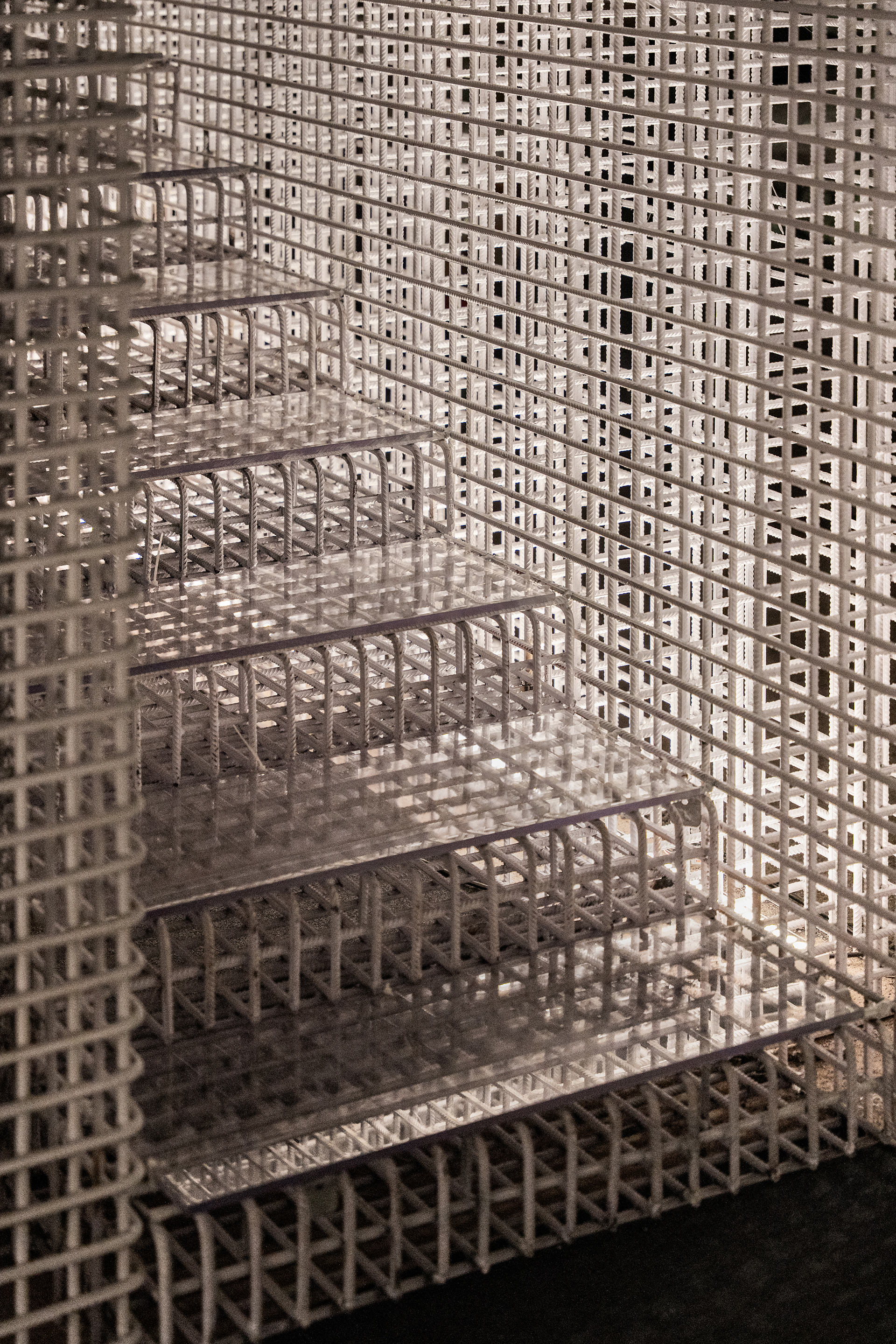 Glass shelving embedded within white lattice screen walls casting patterned shadows