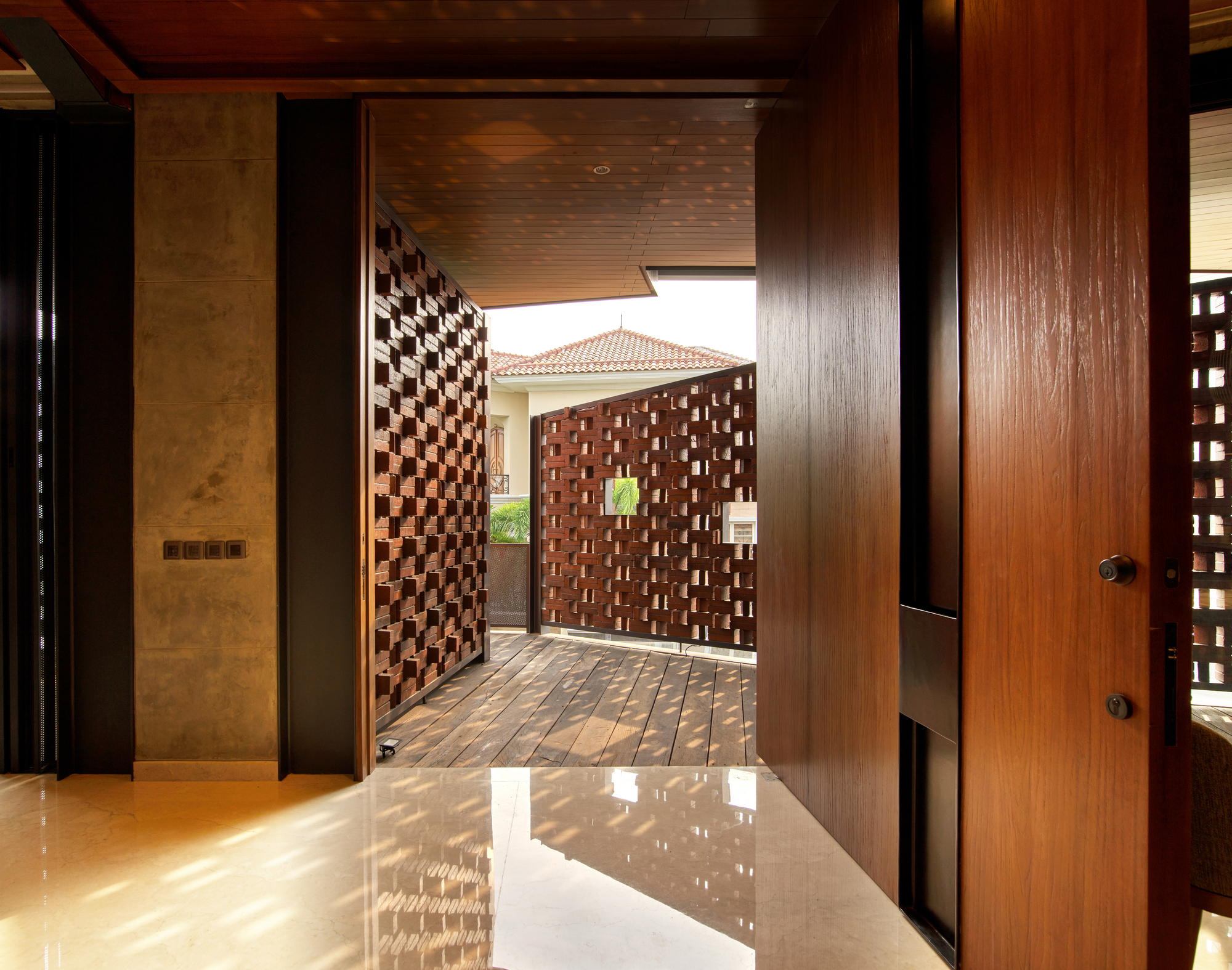 View through timber doorway to exterior courtyard framed by basketweave brick screens in daylight