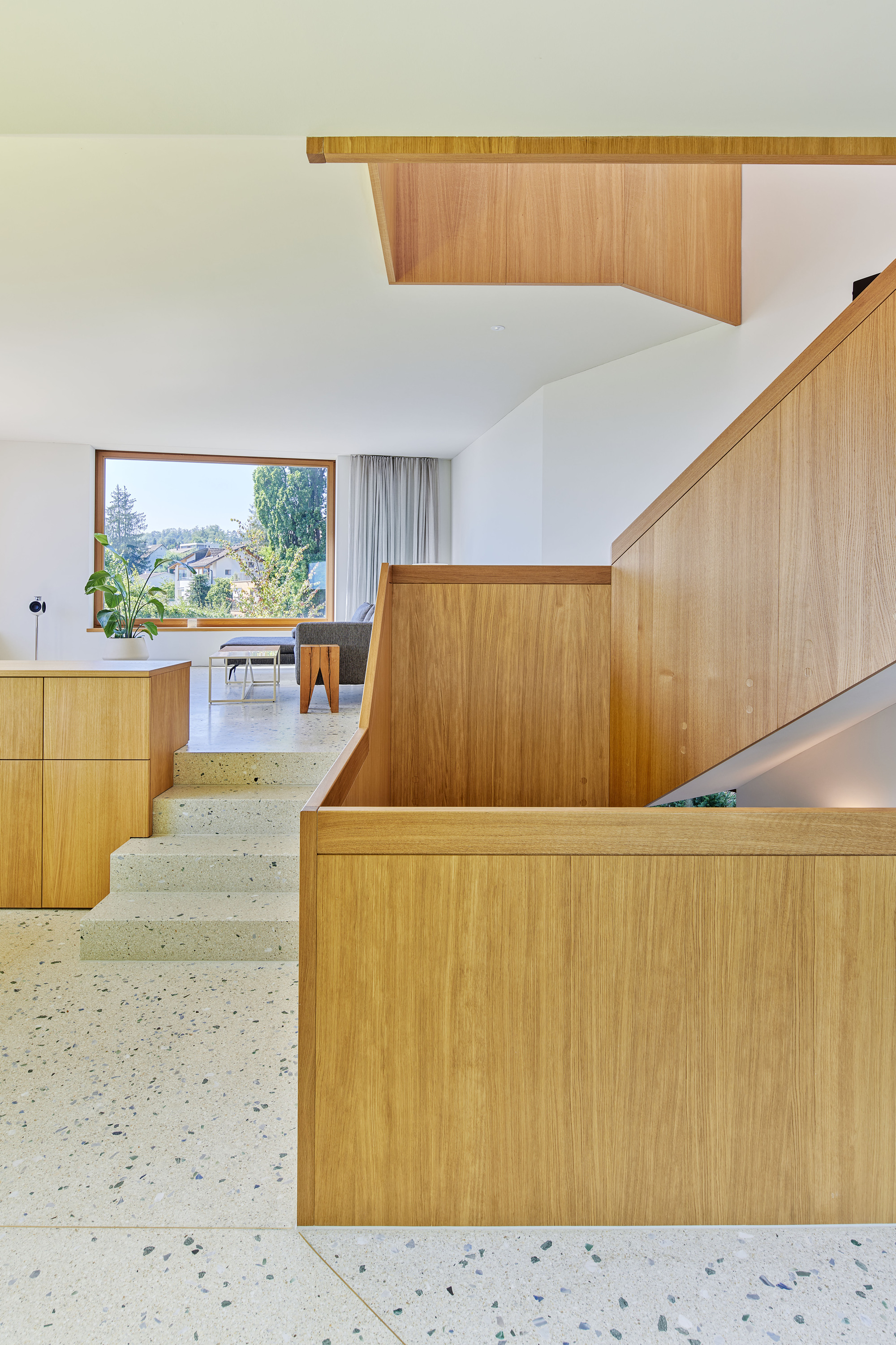 Interior view of timber cabinetry and stairwell with terrazzo flooring under a vaulted ceiling
