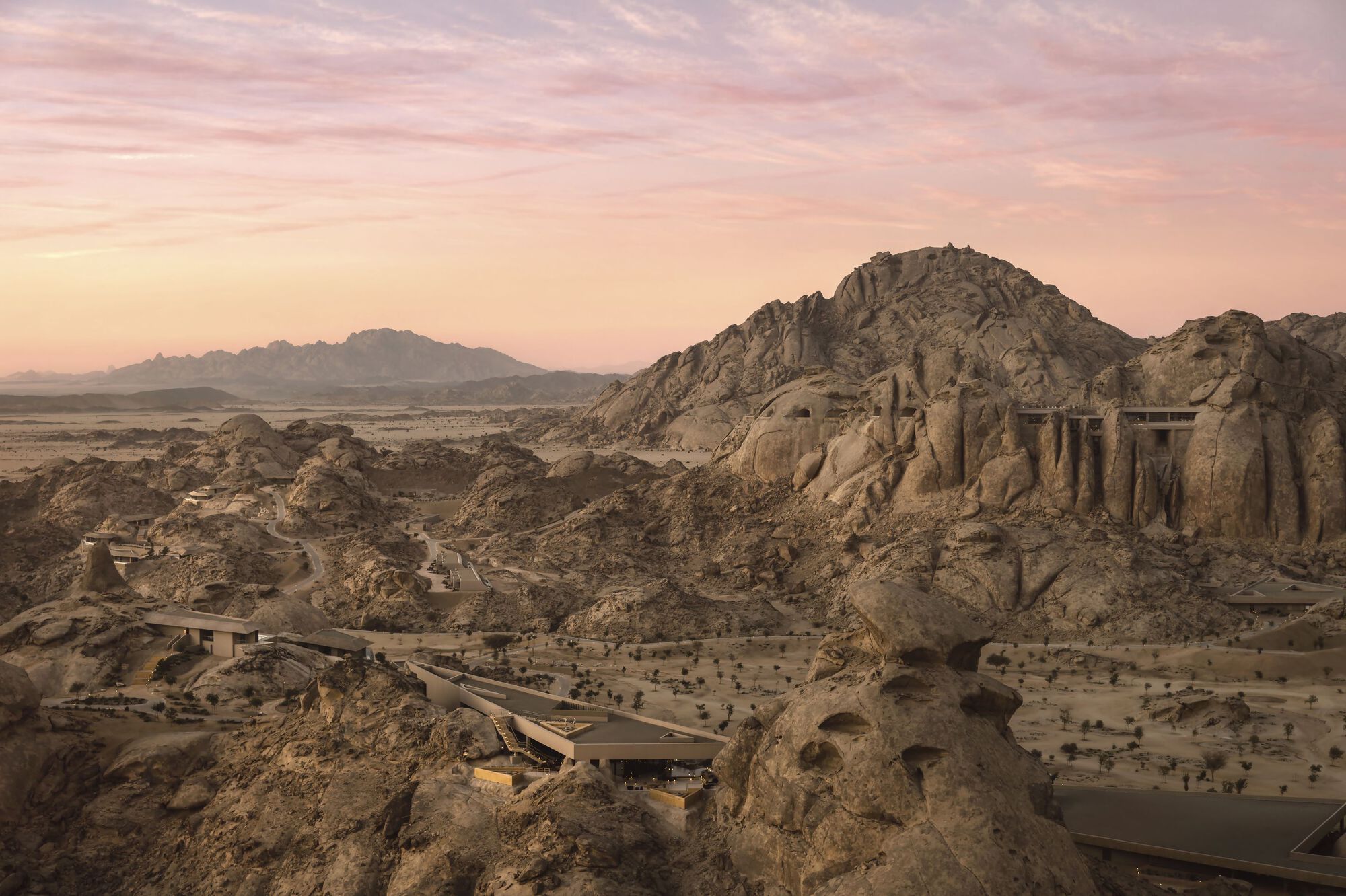 Elevated concrete bridge extending across the desert terrain toward a carved stone outcrop at dusk