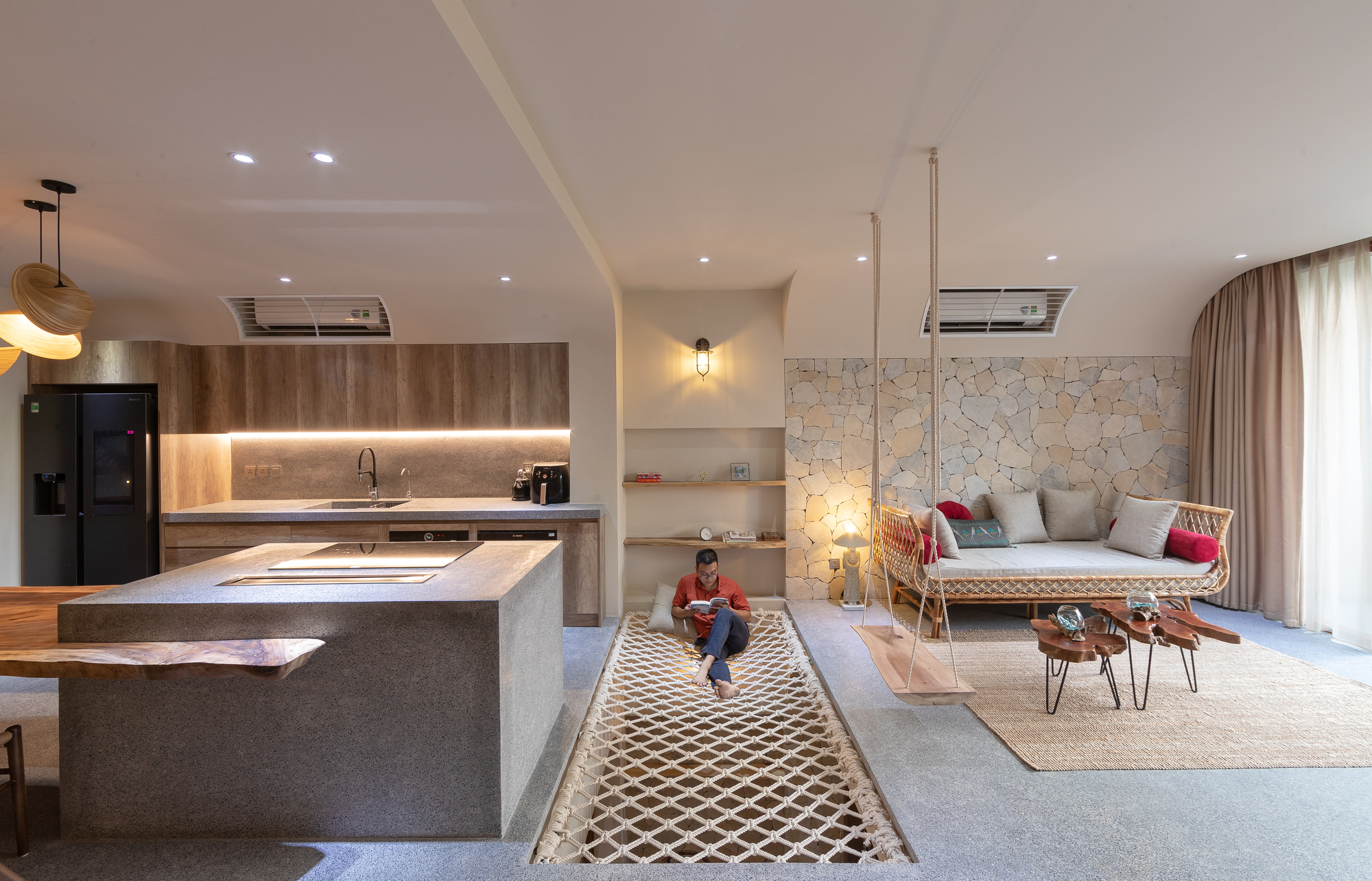 Open living area with kitchen island, irregular stone accent wall and child sitting on patterned rug