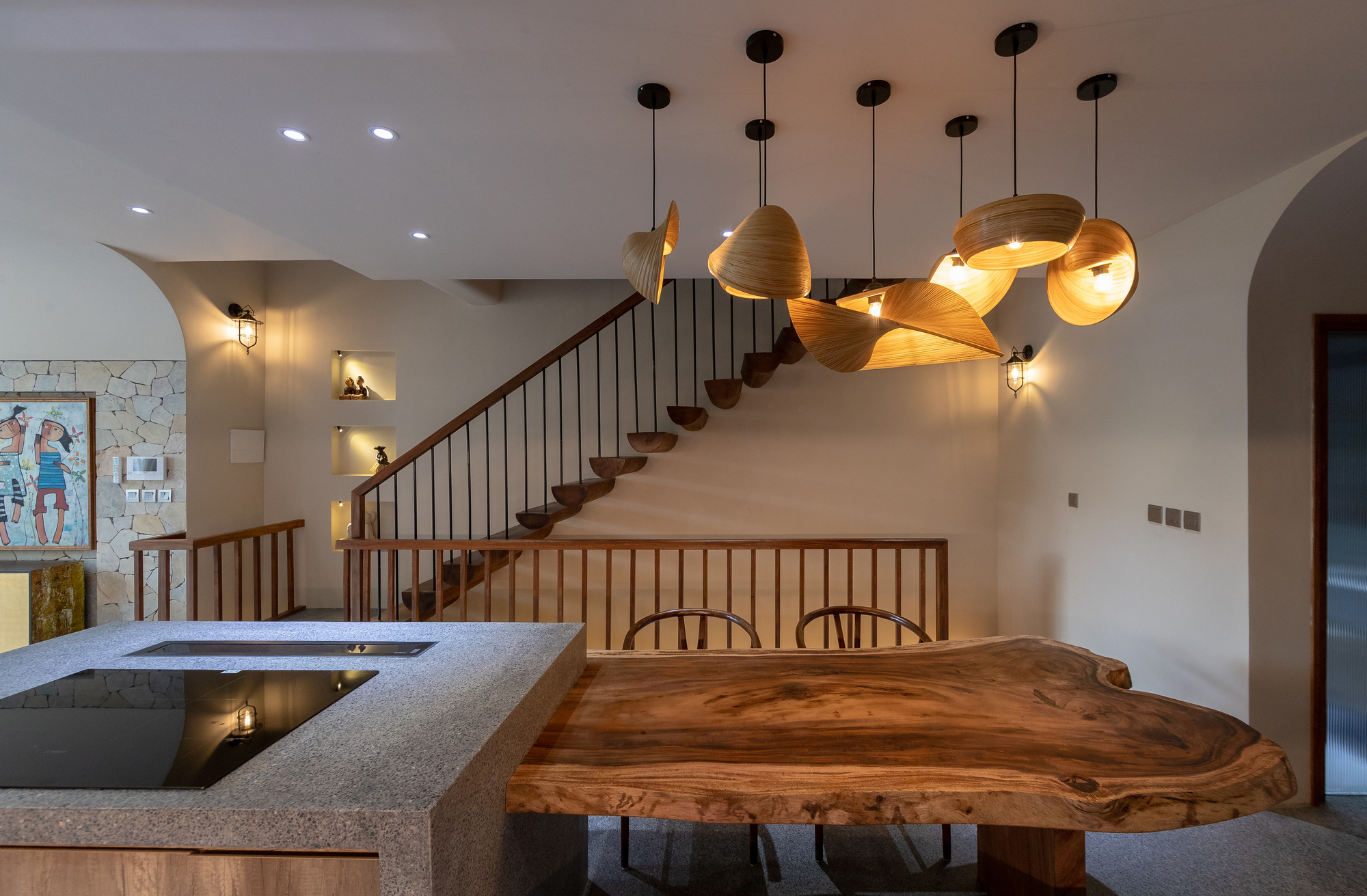 Sculptural cluster of laminated wood pendant lights suspended above the live-edge dining table and terrazzo counter