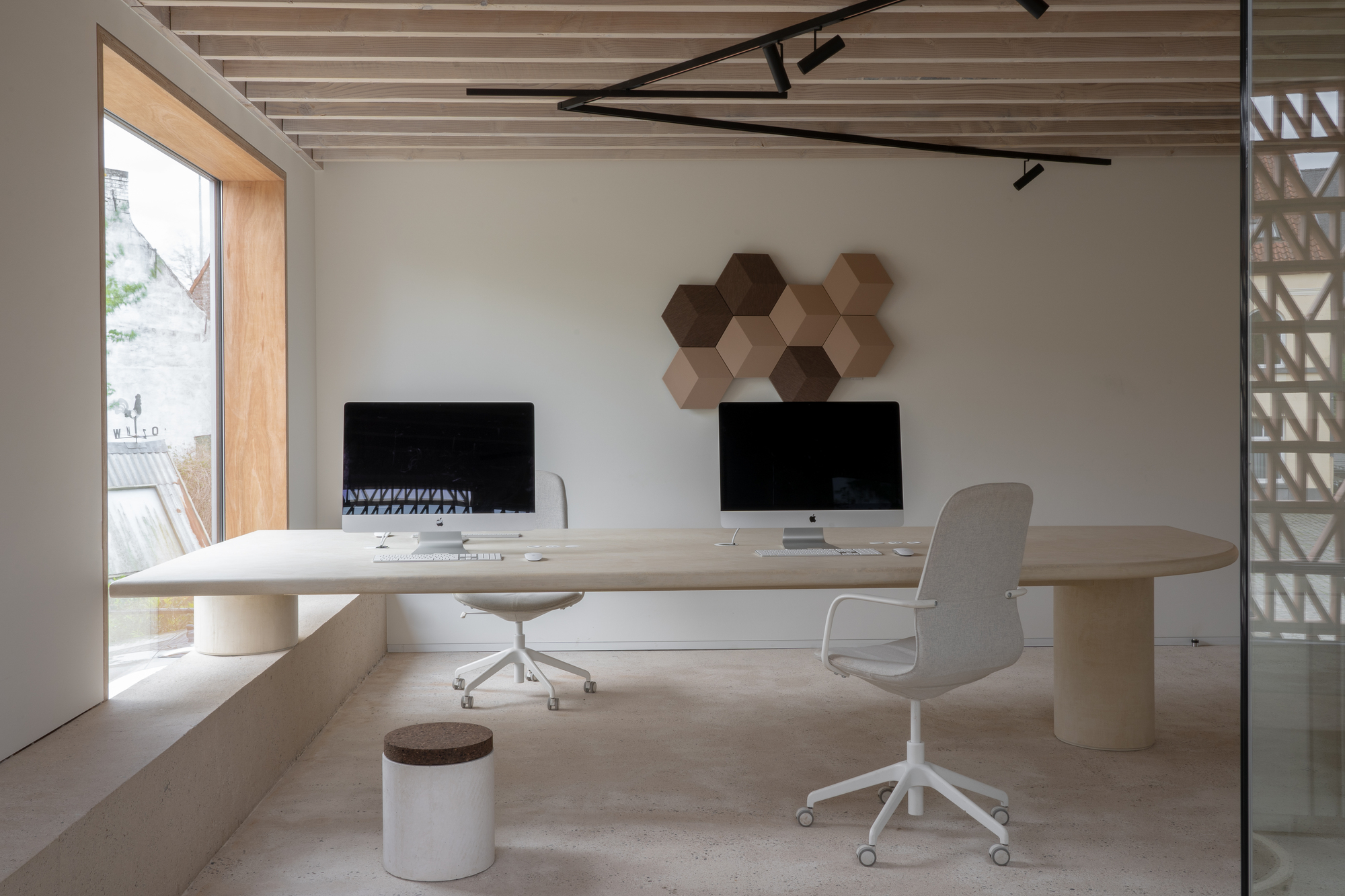 Office with light wood desk, exposed timber ceiling joists and hexagonal wall panels
