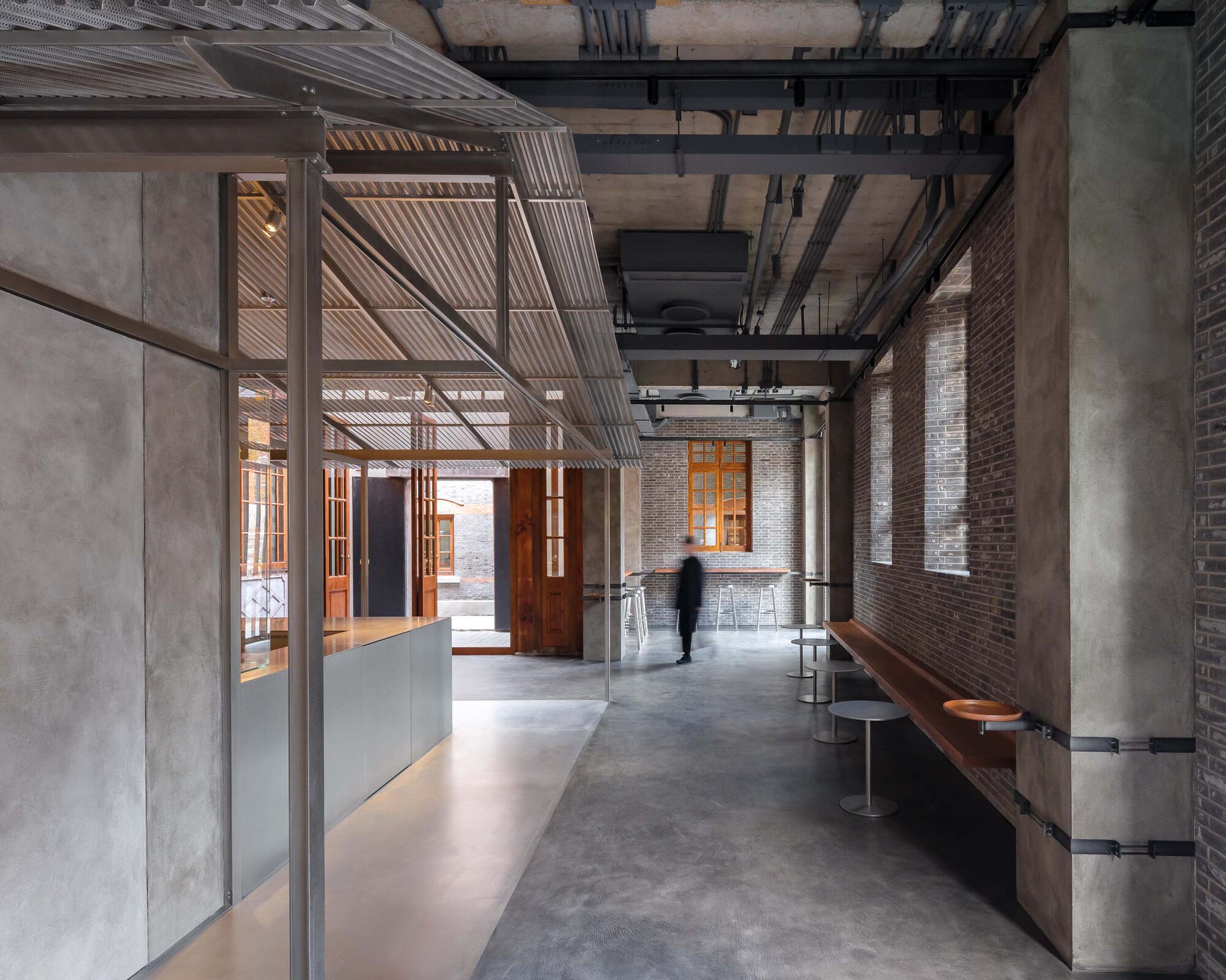 Interior corridor with exposed brick walls, concrete columns, suspended timber slat ceiling and polished concrete floor