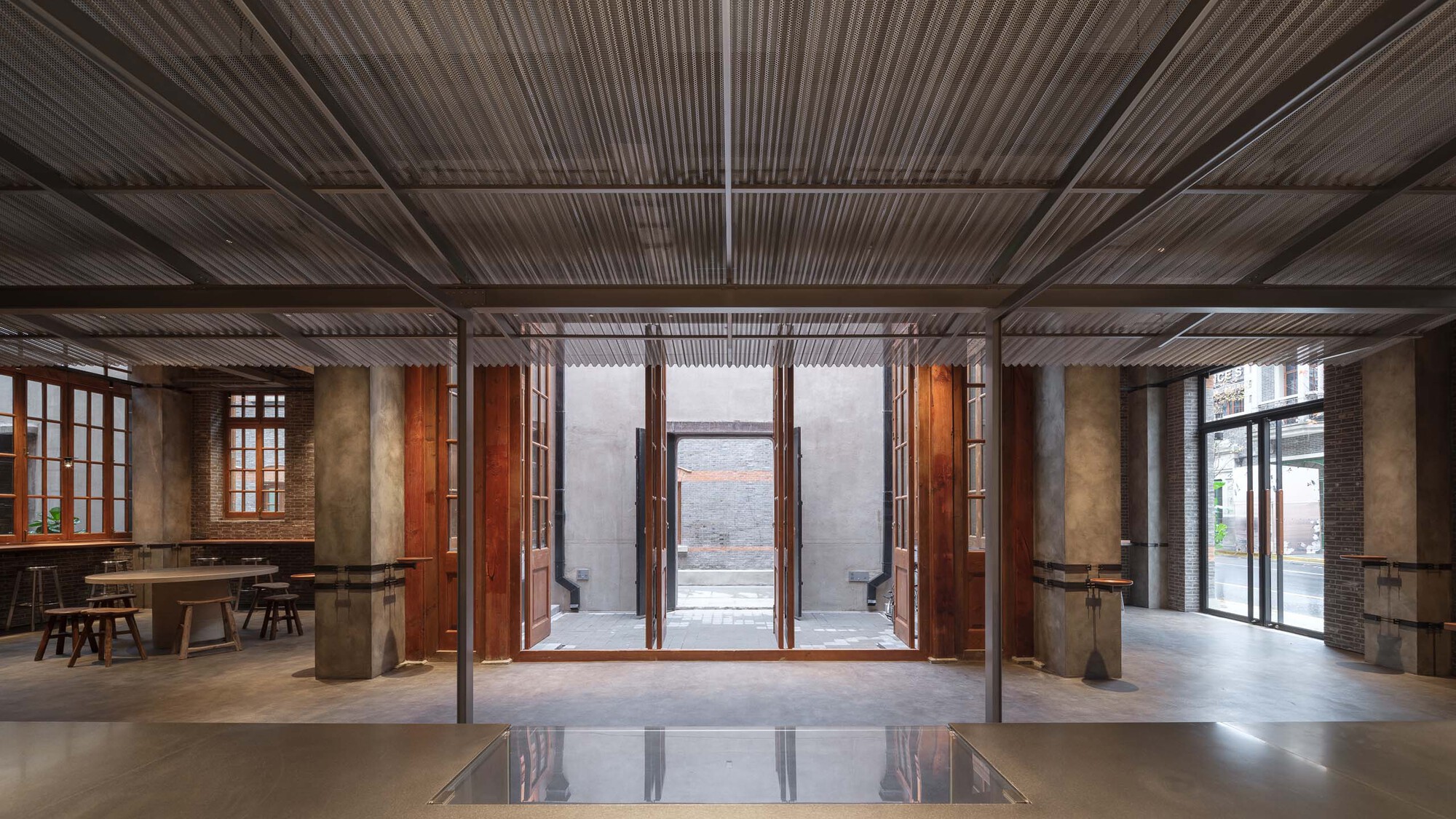 Central hall with timber-louvered ceiling looking toward large folding doors opening to exterior courtyard