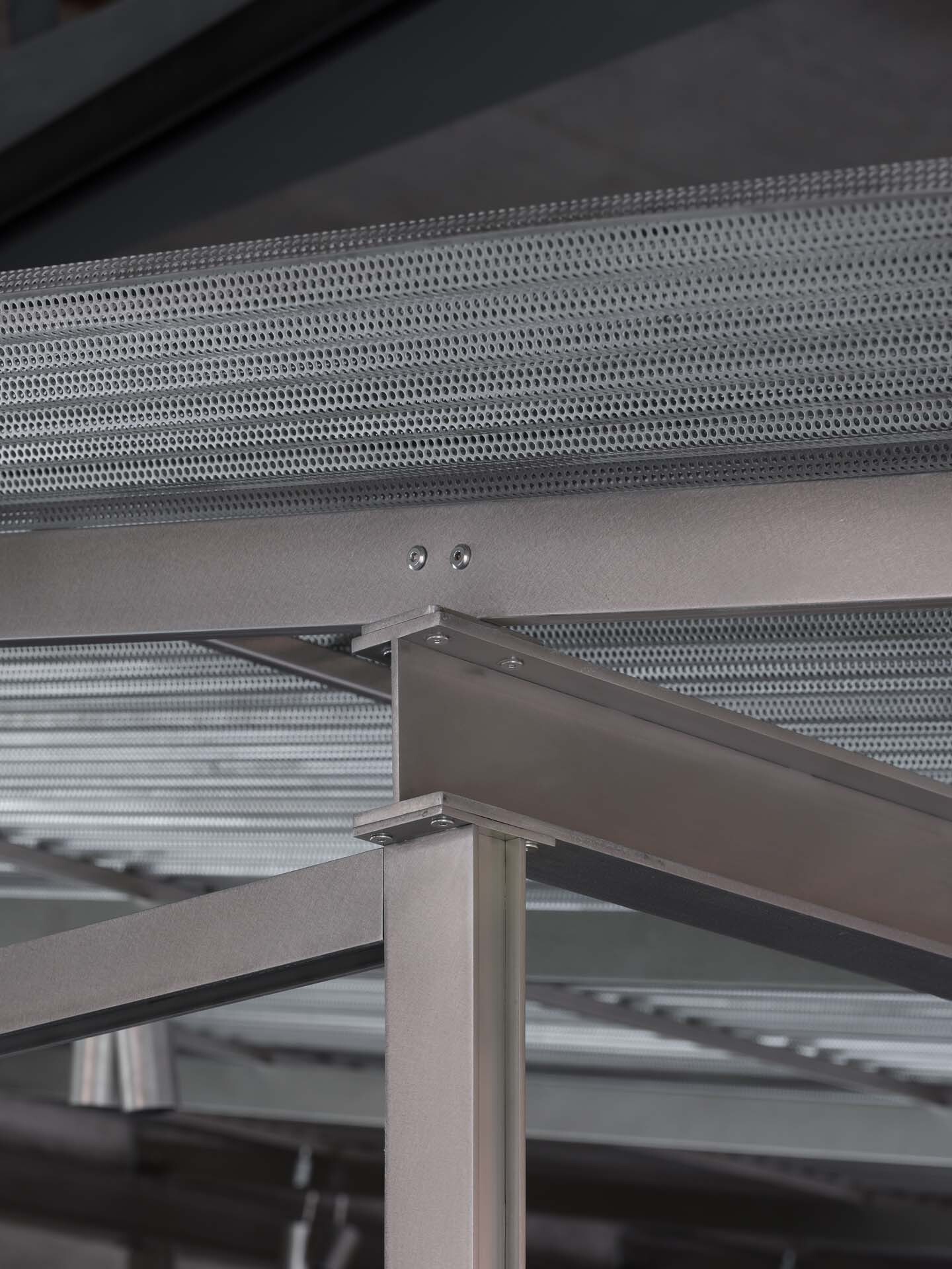 Detail of perforated metal ceiling panel connection with steel frame and concrete beam junction