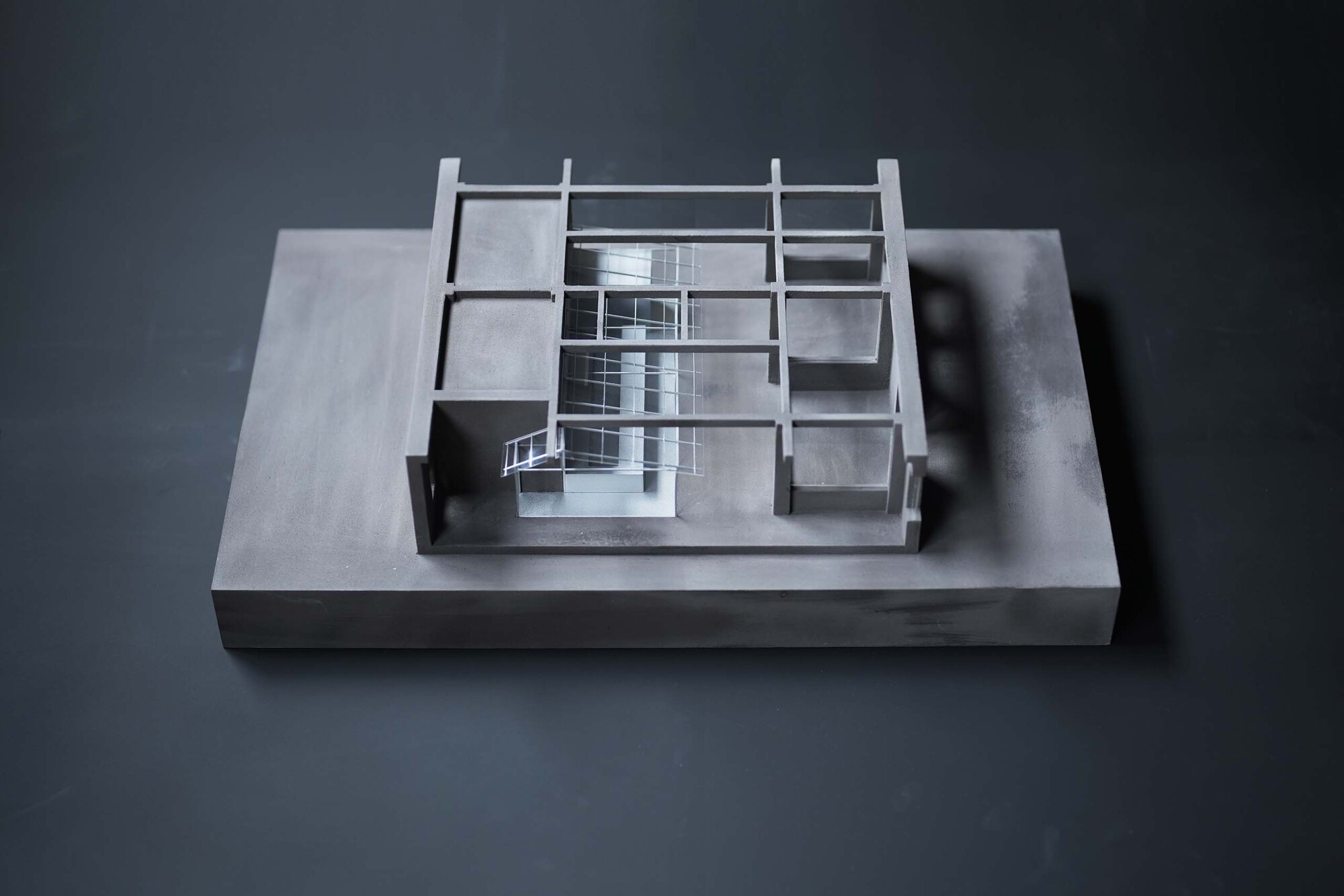 Physical model revealing interior spatial organization through transparent acrylic walls and steel frame
