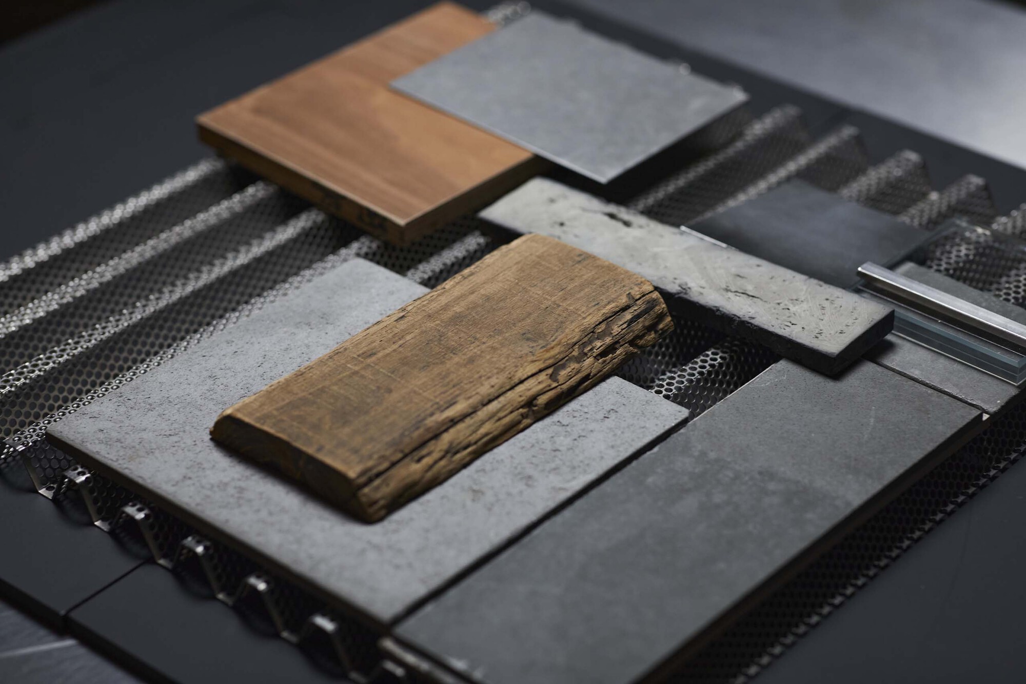 Material sample board with timber, concrete, metal mesh, and stone arranged on woven textile