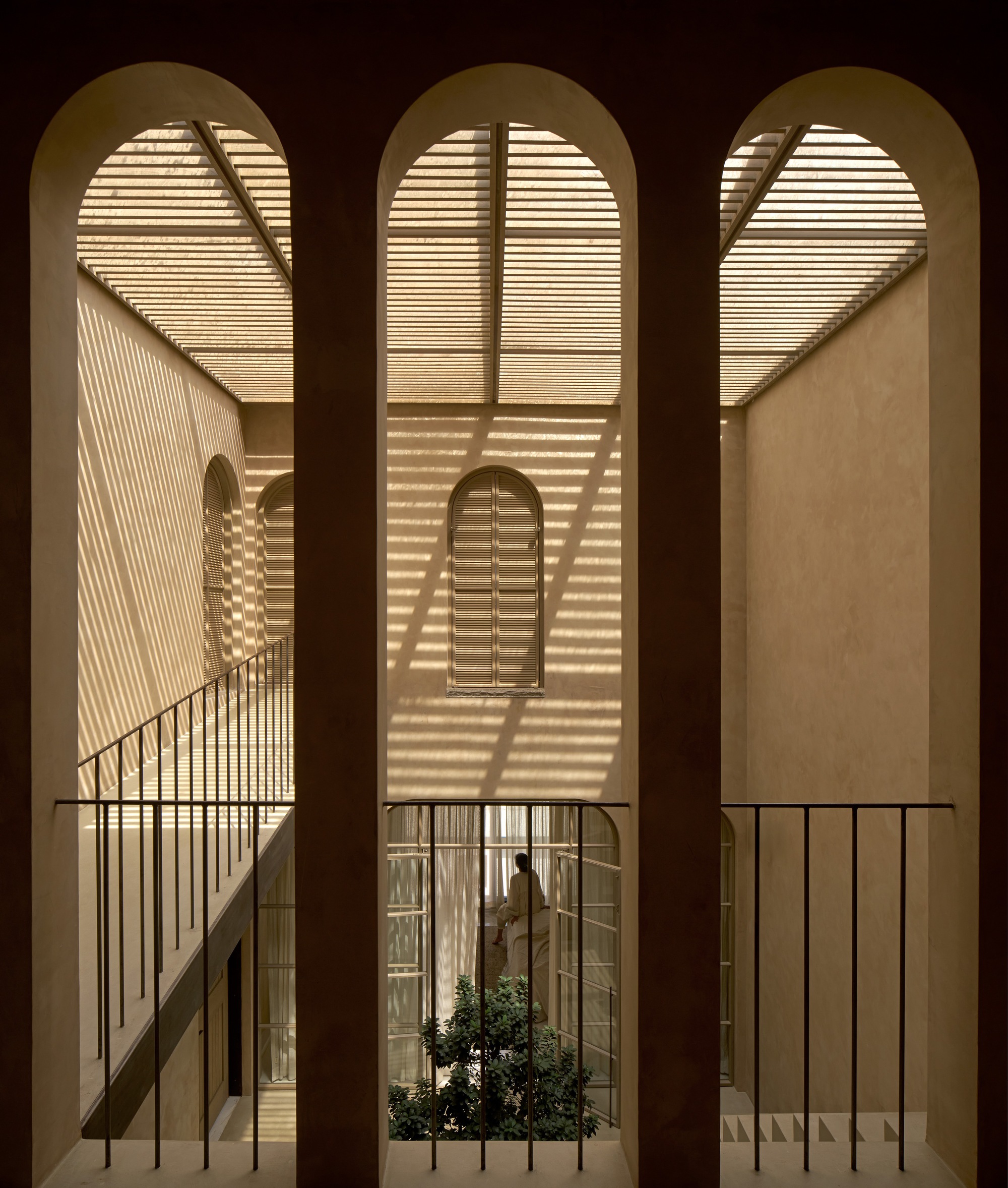 Triple arched openings framing the stairwell and courtyard with slatted light patterns at night
