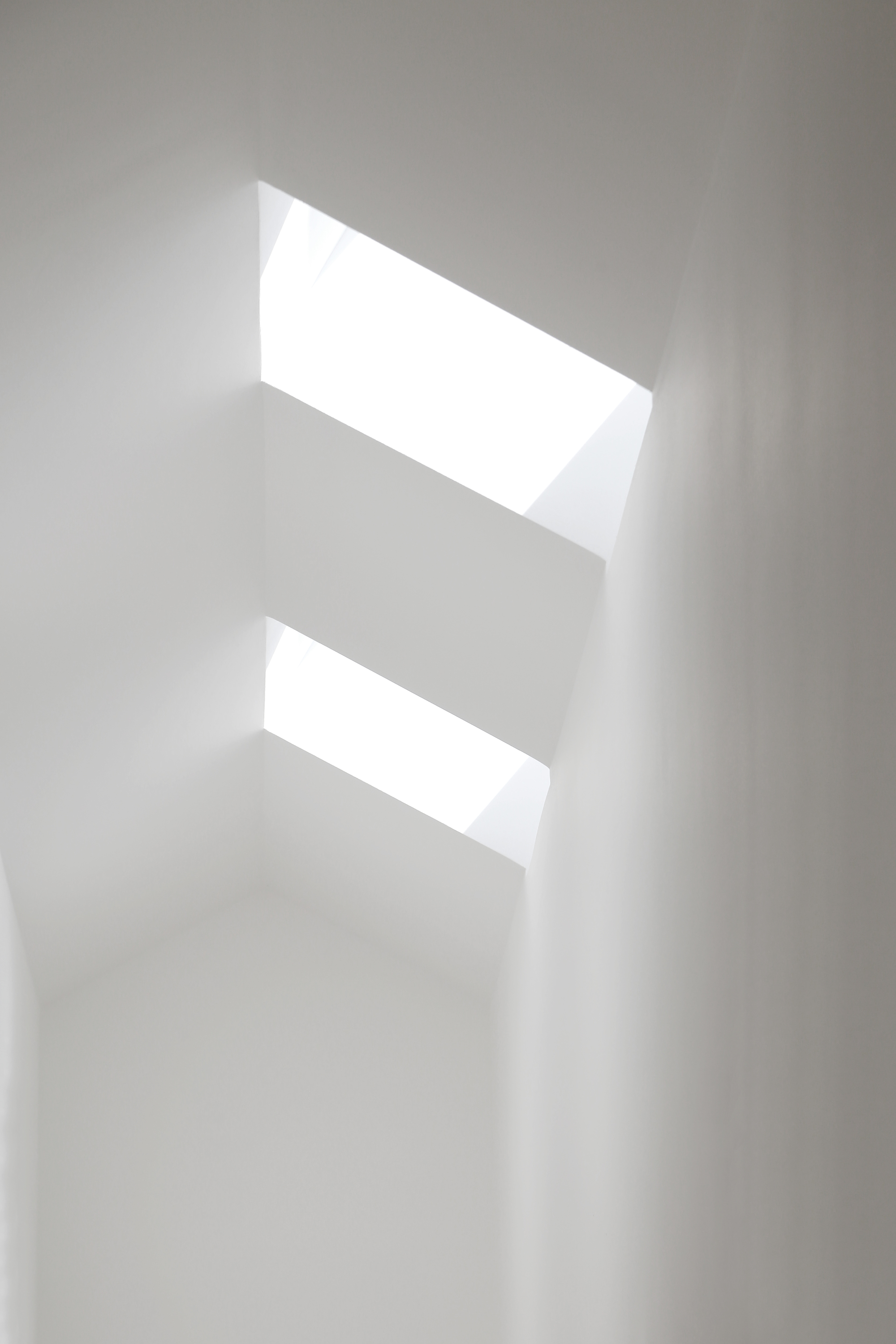 Two angled skylights punched through a white plaster ceiling casting soft natural light