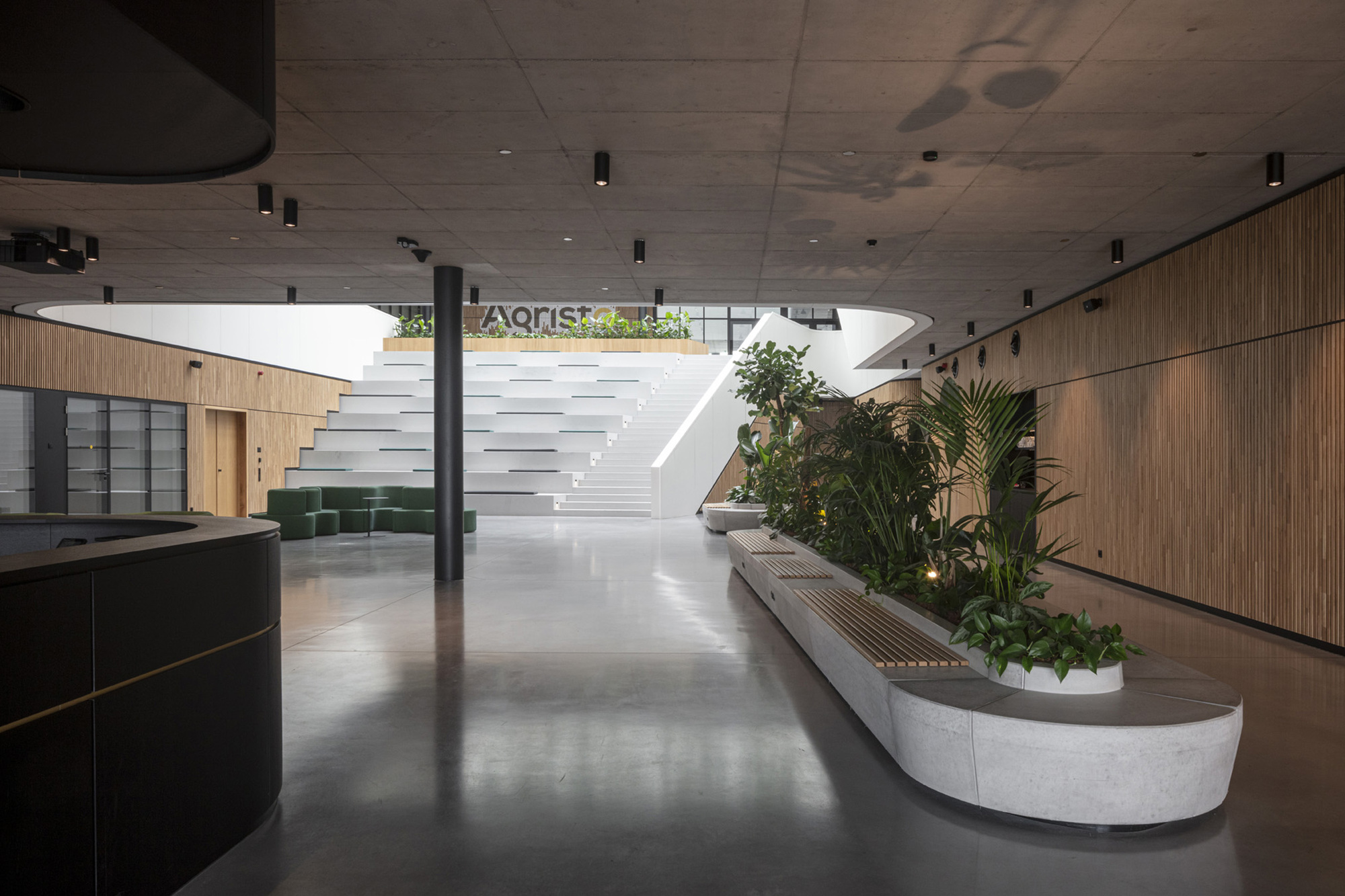 Reception lobby with floating staircase, curved planter beds, and polished concrete floor
