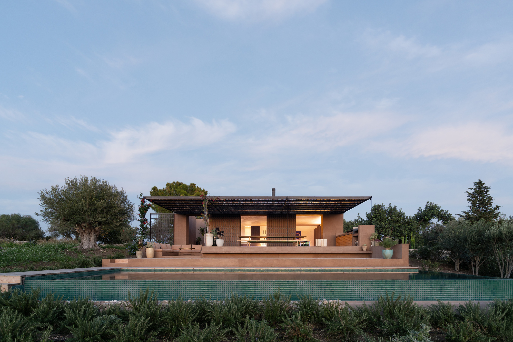 Pool terrace with overhanging flat roof supported by steel columns at dusk