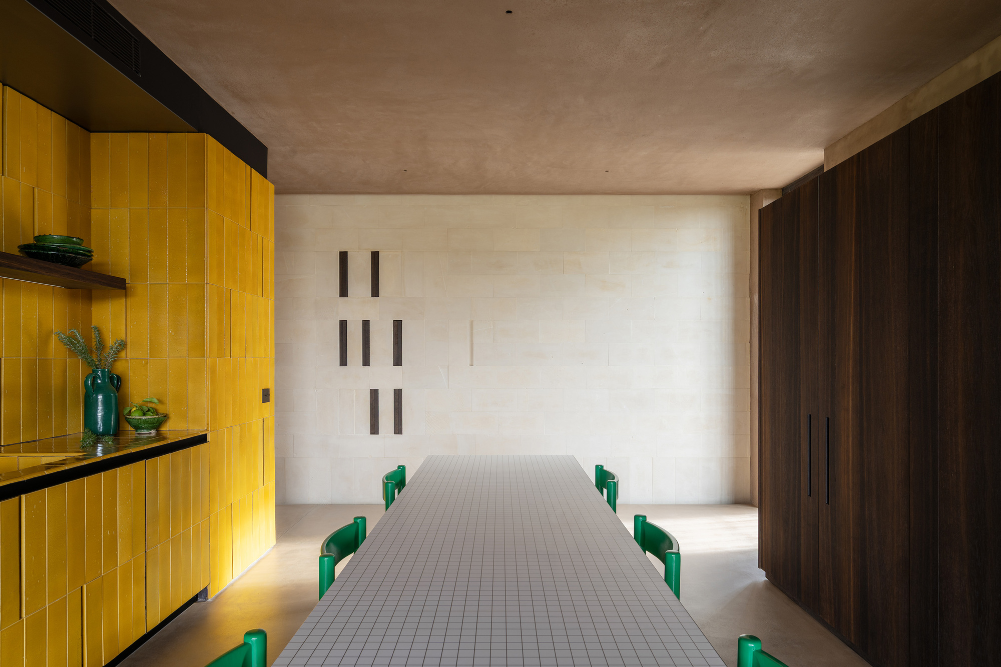 Corridor with white mosaic tile floor and yellow paneled wall illuminated by concealed lighting