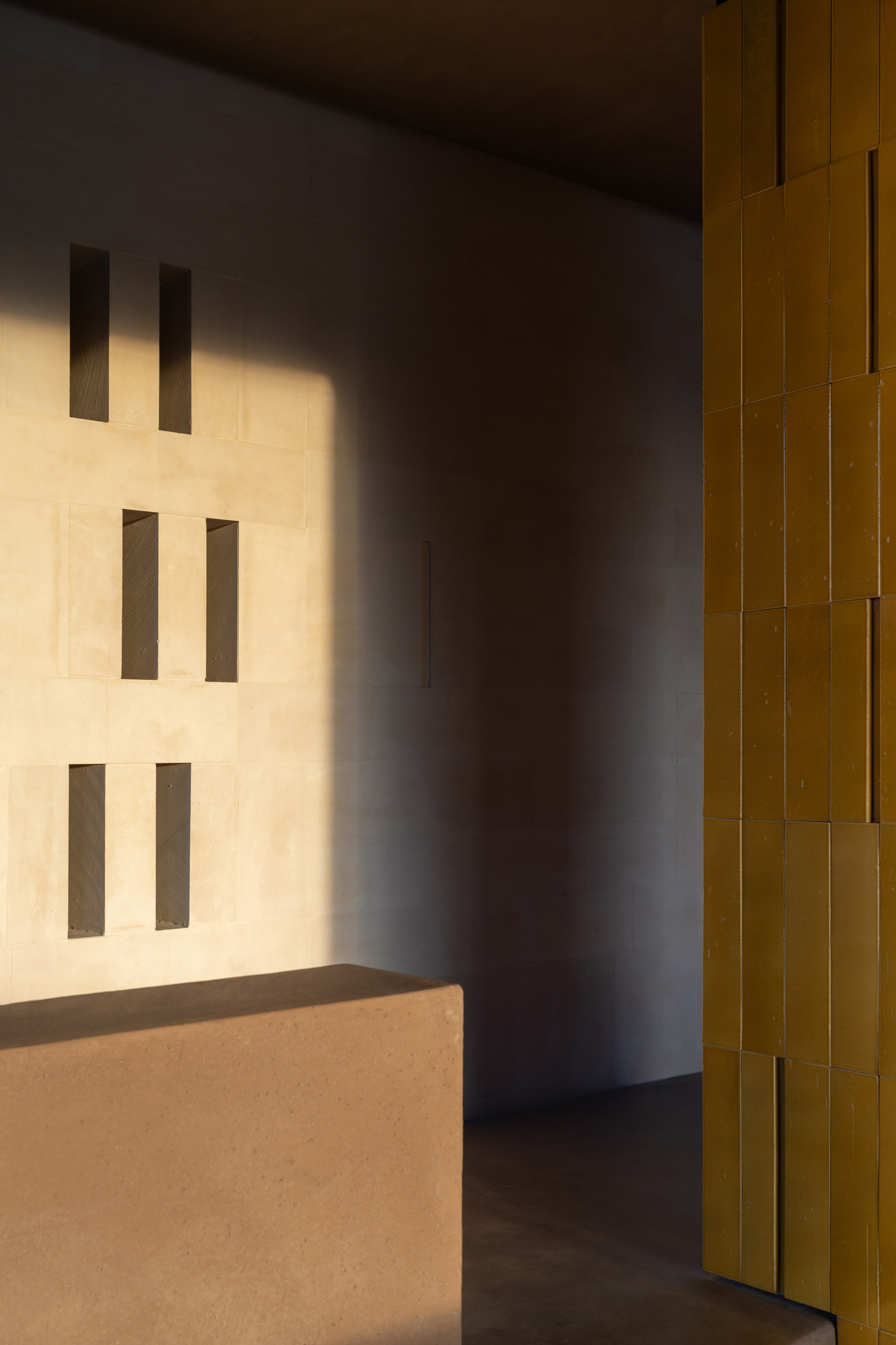 Corner detail showing rectangular wall openings and yellow glazed tile column in afternoon light