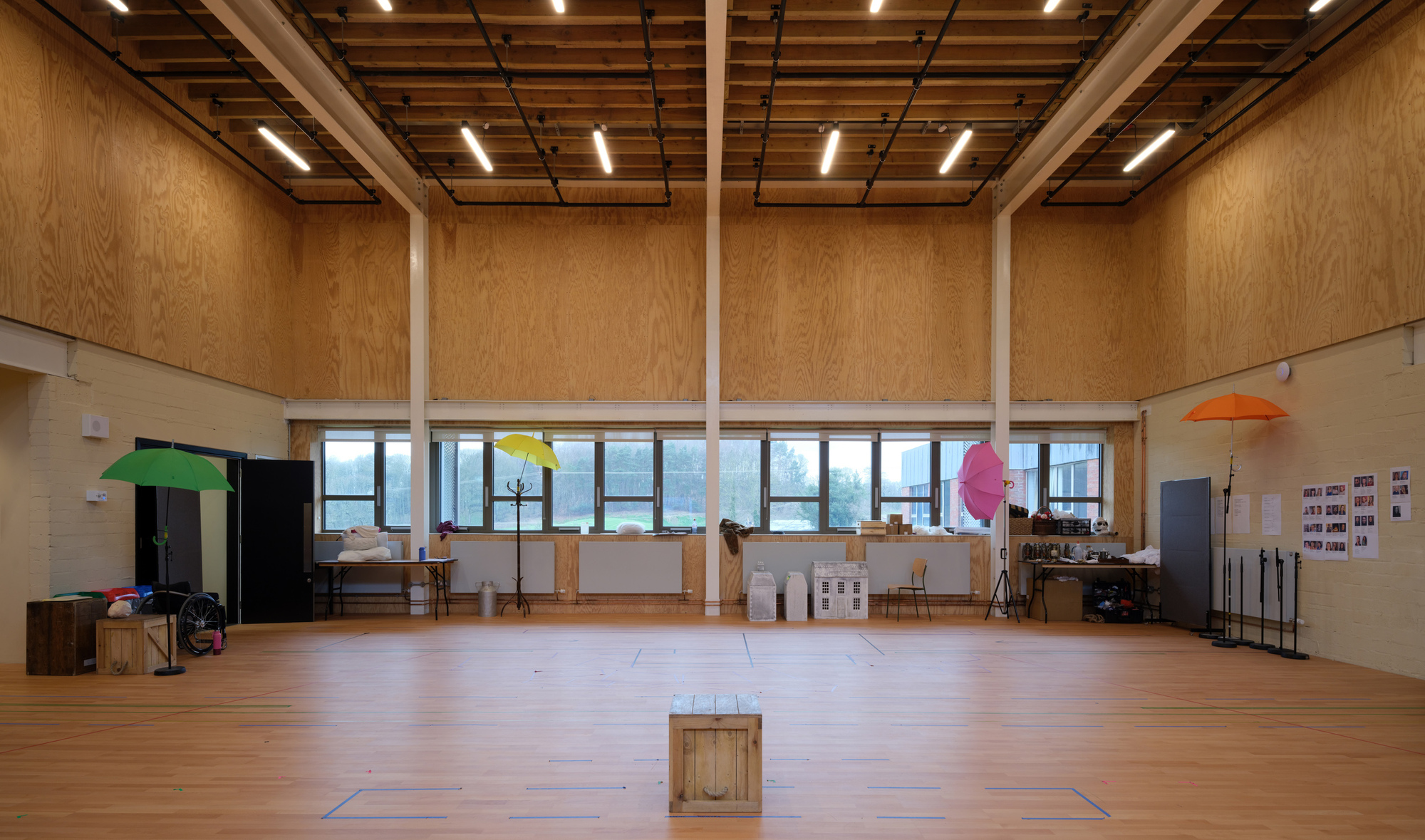 Large studio space with plywood walls, exposed timber ceiling structure, and continuous clerestory windows