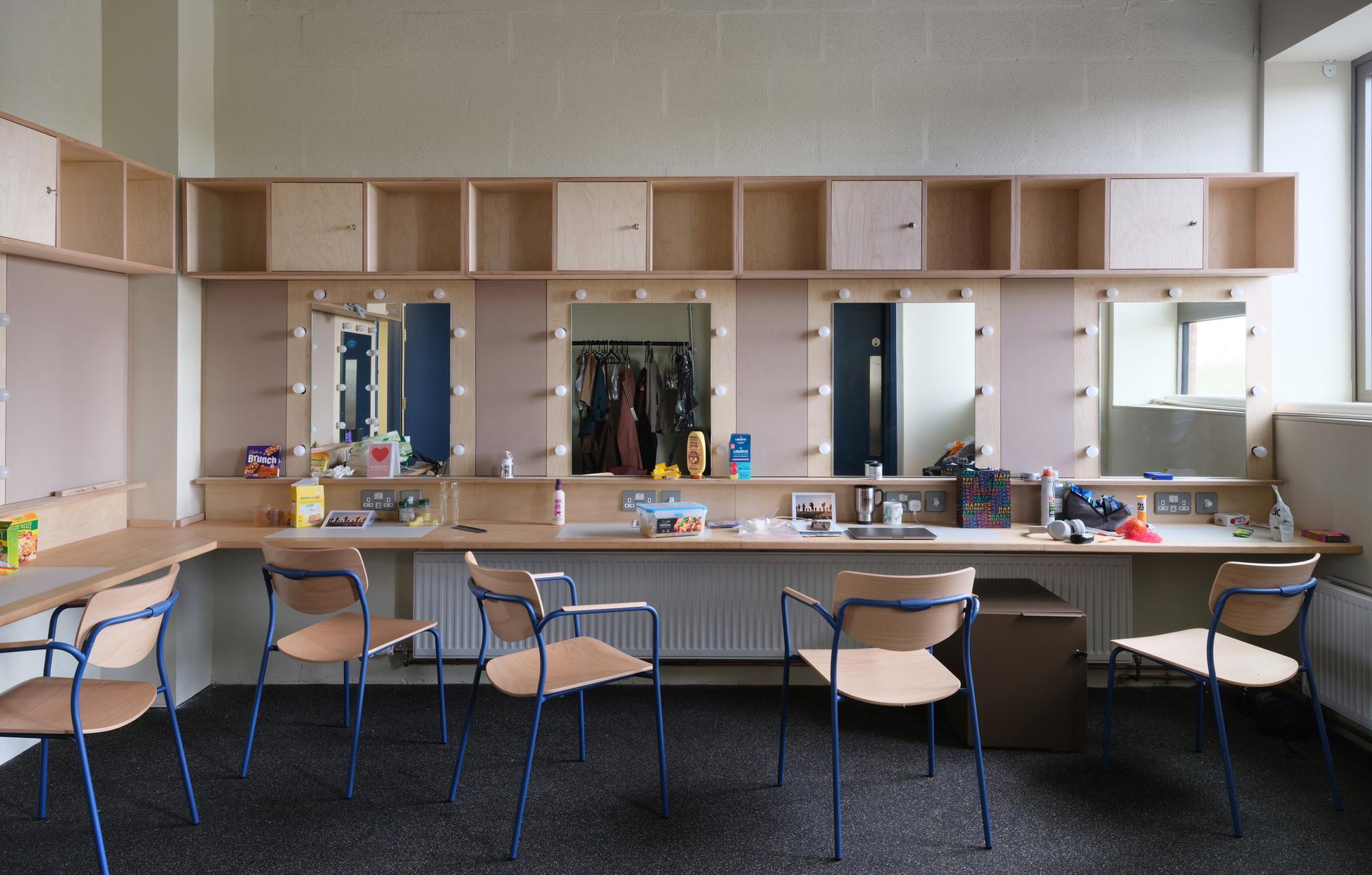 Built-in plywood vanity unit with integrated mirrors, storage cubbies, and a row of chairs below
