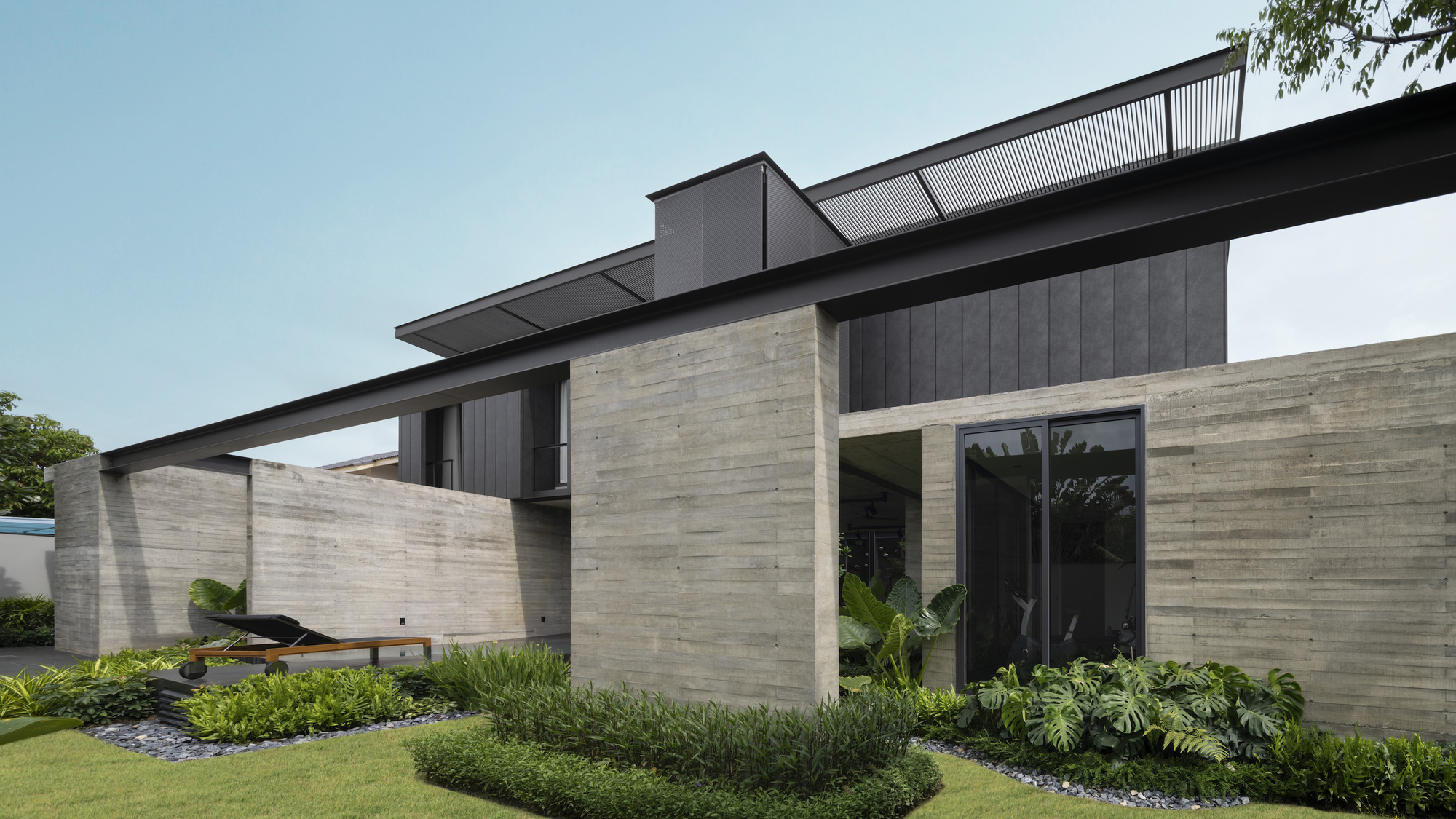 Street-facing corner showing horizontally striated stone walls and dark metal cladding with planted garden beds