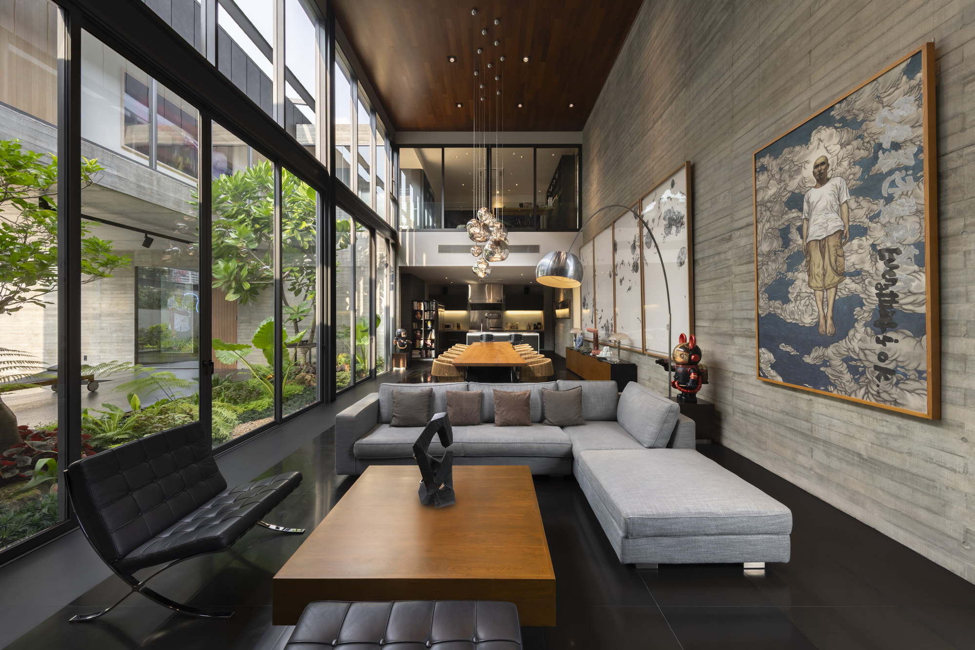 Double-height living room with floor-to-ceiling glazing overlooking an interior garden courtyard