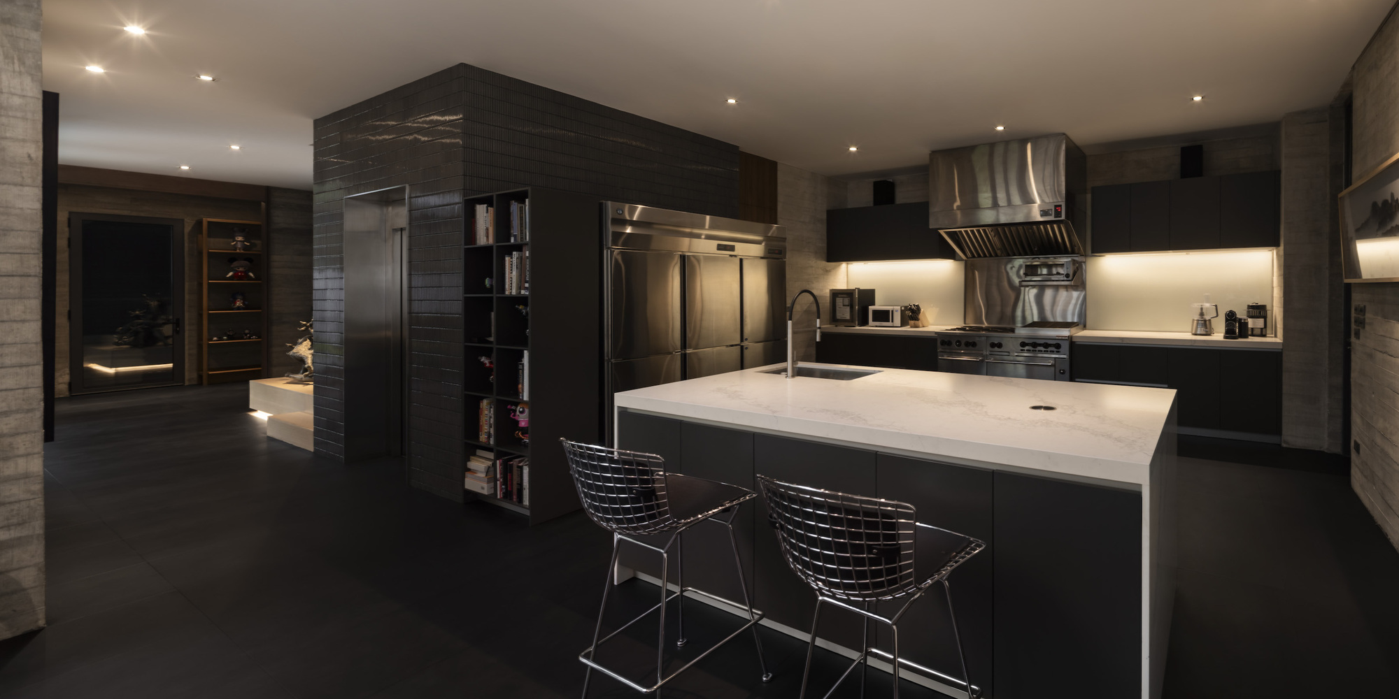 Kitchen with white stone island and dark wood cabinetry under recessed ceiling lighting